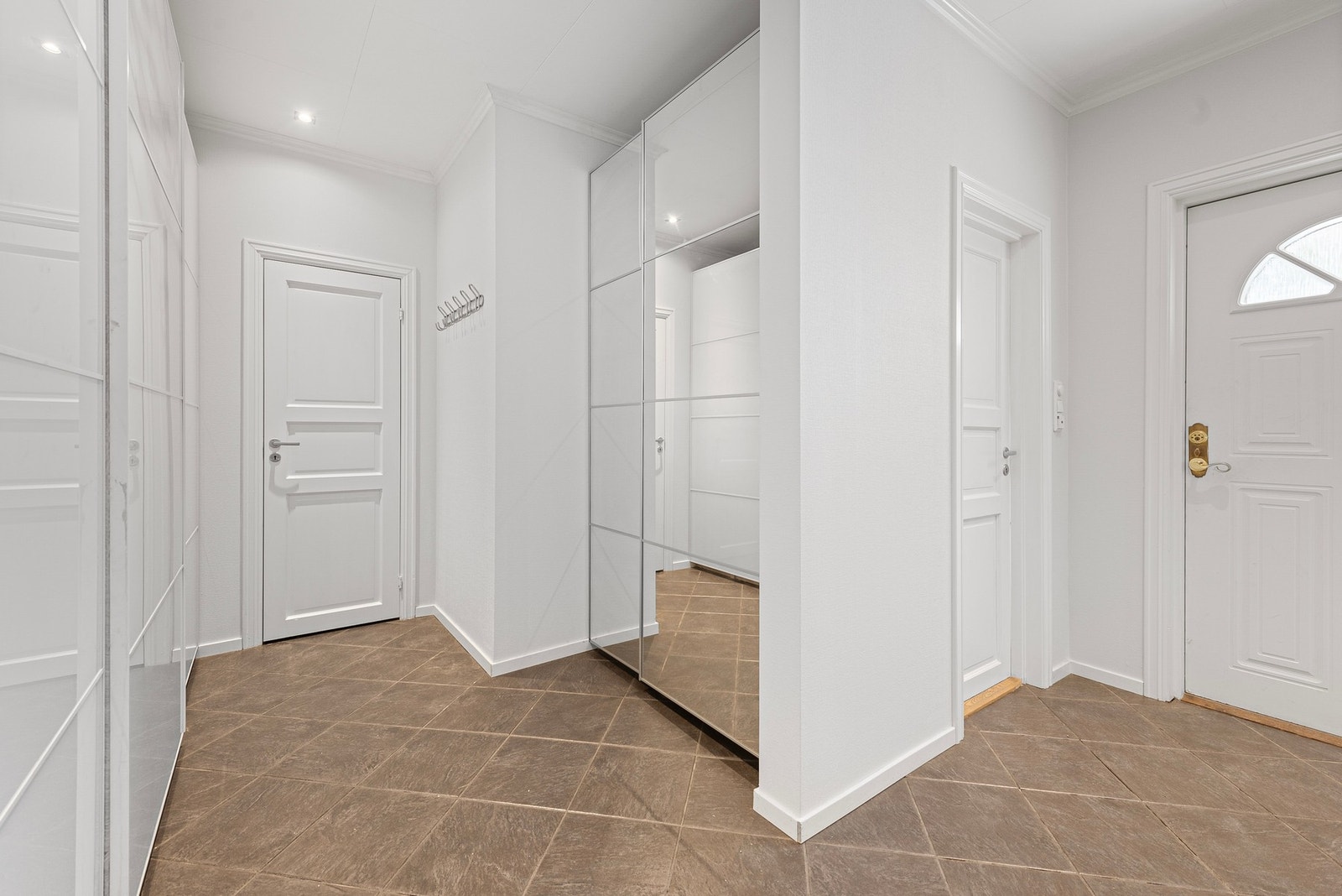 Her er et tidligere soverom åpnet opp for romslig hall med skyvedørsgarderober og innvendig bod Galleribilde