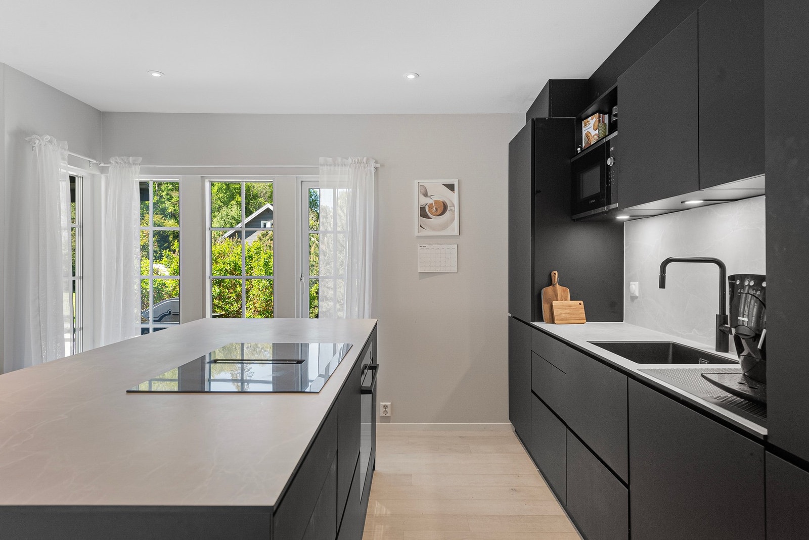 Rikelig med skap- og benkplass og platetopp med ventilator nedfelt i kjøkkenøyen Galleribilde