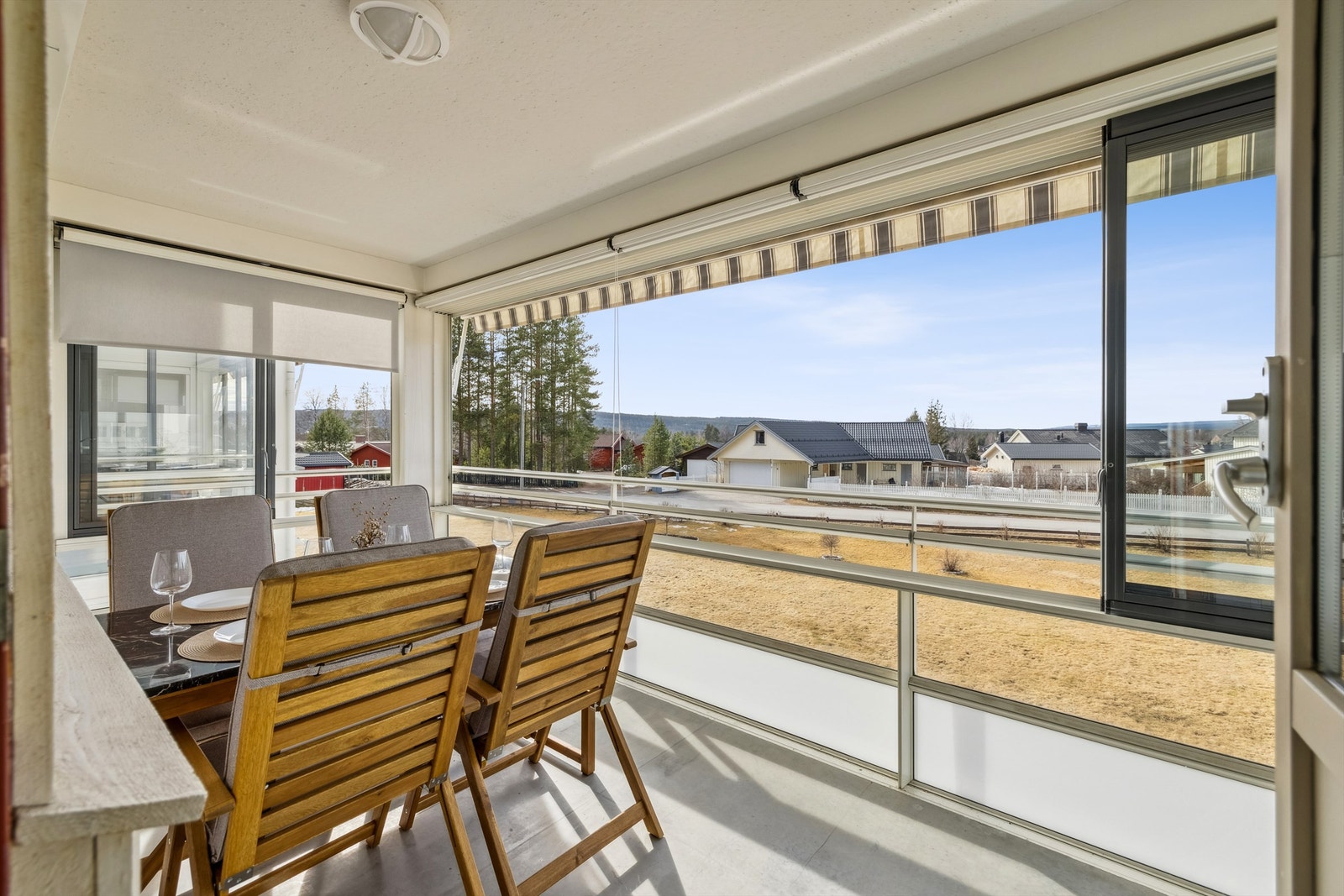 Stor innglasset balkong med innvendig solskjerming og motorisert terrassemarkise. Galleribilde