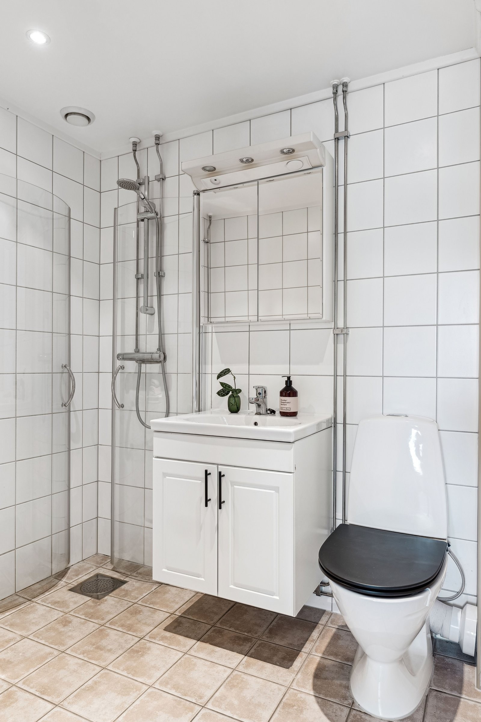 Lyst flislagt baderom med gulvvarme og downlights i himling. Galleribilde