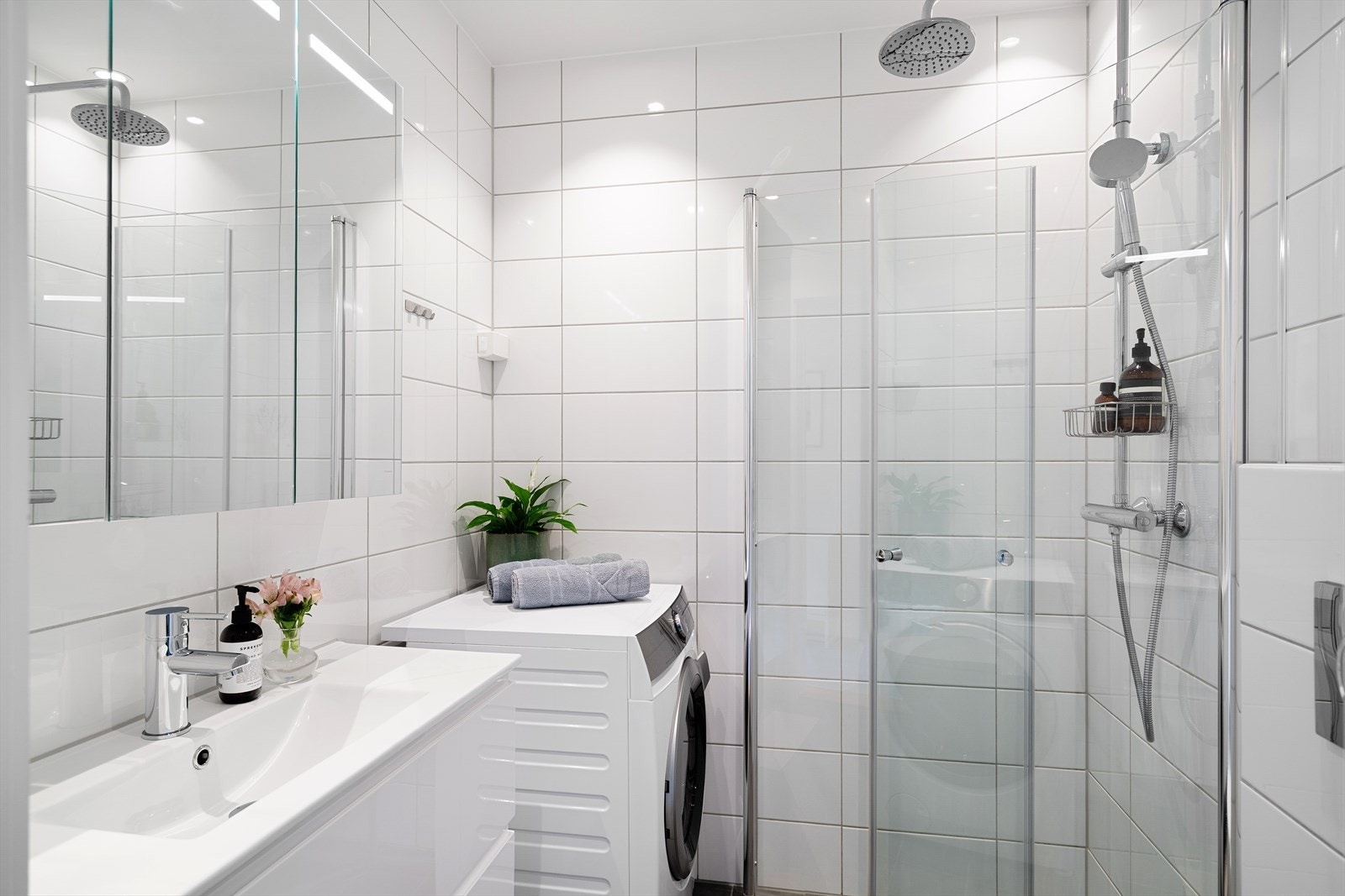 Pent baderom med flis på gulv og vegger, samt gulvvarme. Utstyrt med innfellbare dusjdører, naturlig avtrekk, opplegg for vaskemaskin, servantskap, stoppekran og veggmontert wc Galleribilde