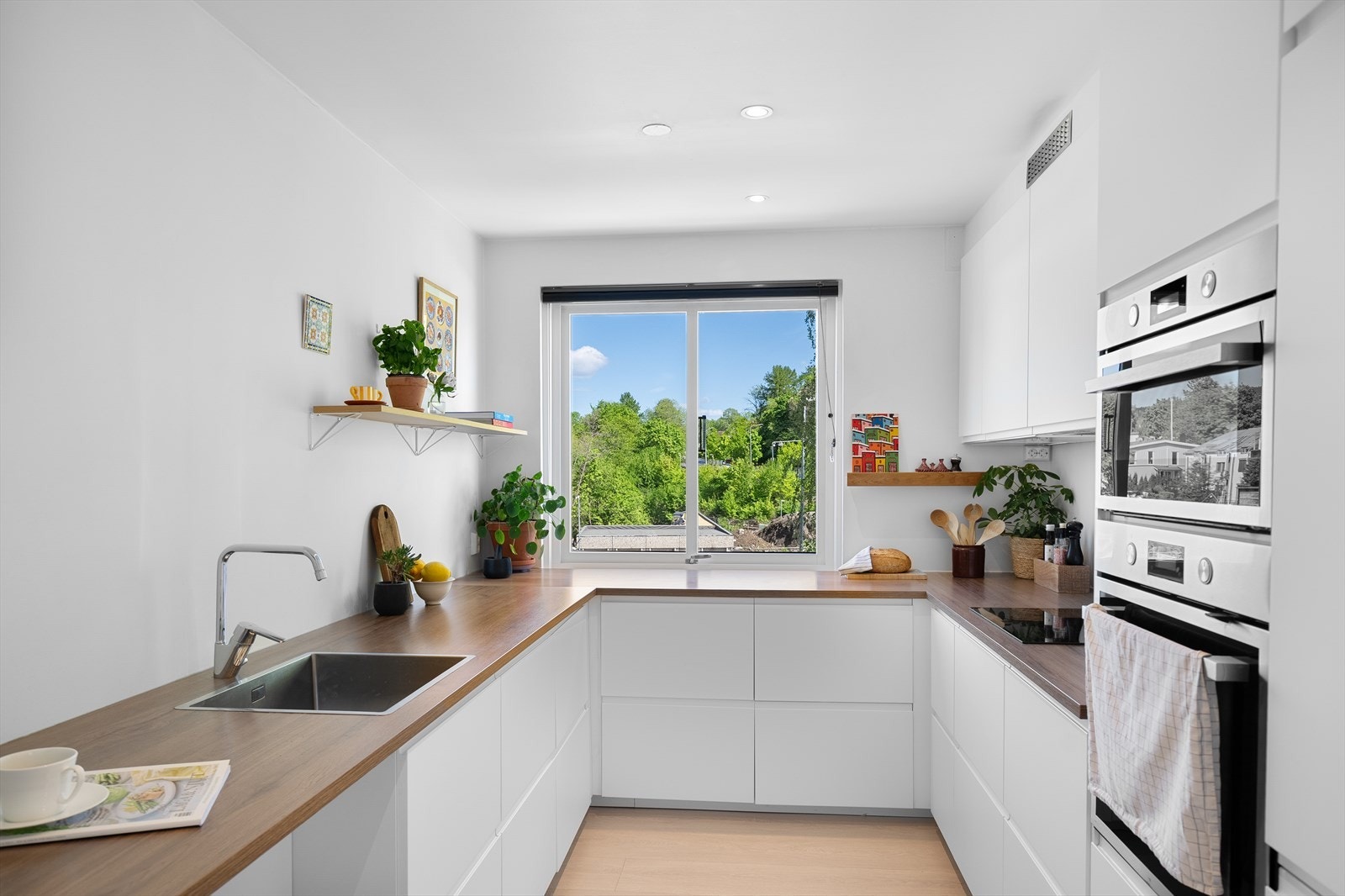 Kjøkkenet fra 2019 fremstår som delikat med glatte fronter, nedsenket vaskekum, og god benk- og skapplass Galleribilde