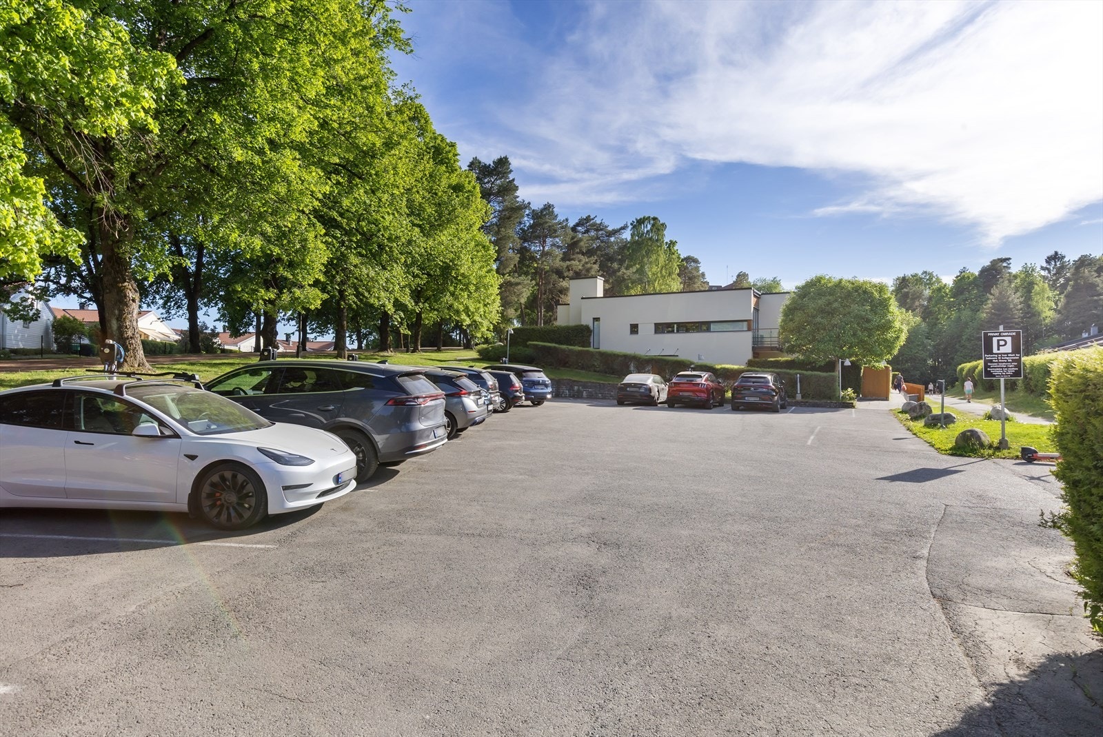 Asfaltert parkeringsplass ved siden av bygget. Boligen disponerer parkeringsplass med elbil-lader. Plassen er merket nr. 16. Galleribilde