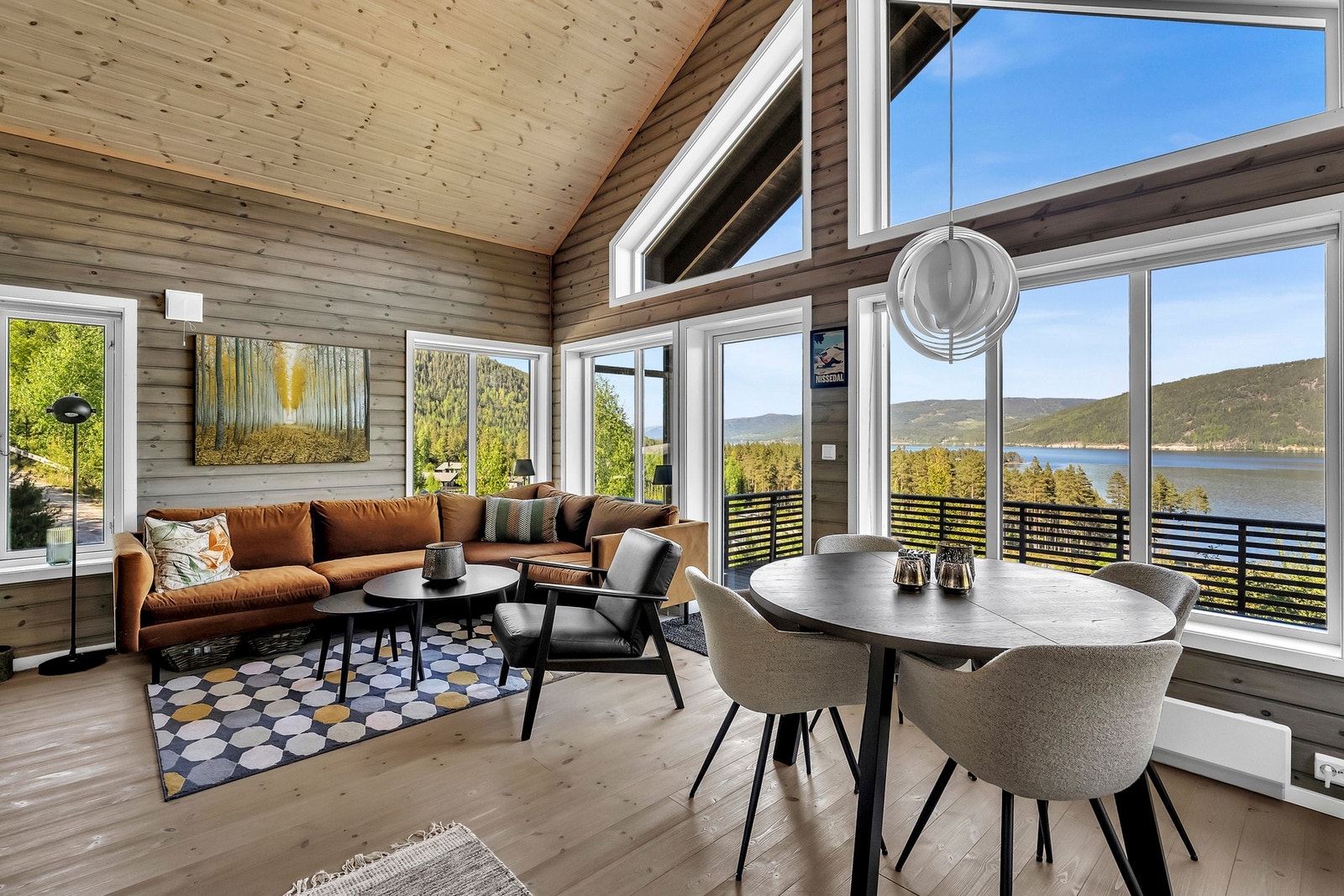 Lys og romslig stue med store vinduer som gir utsikt over Nisser og fjellområdet rundt. Galleribilde