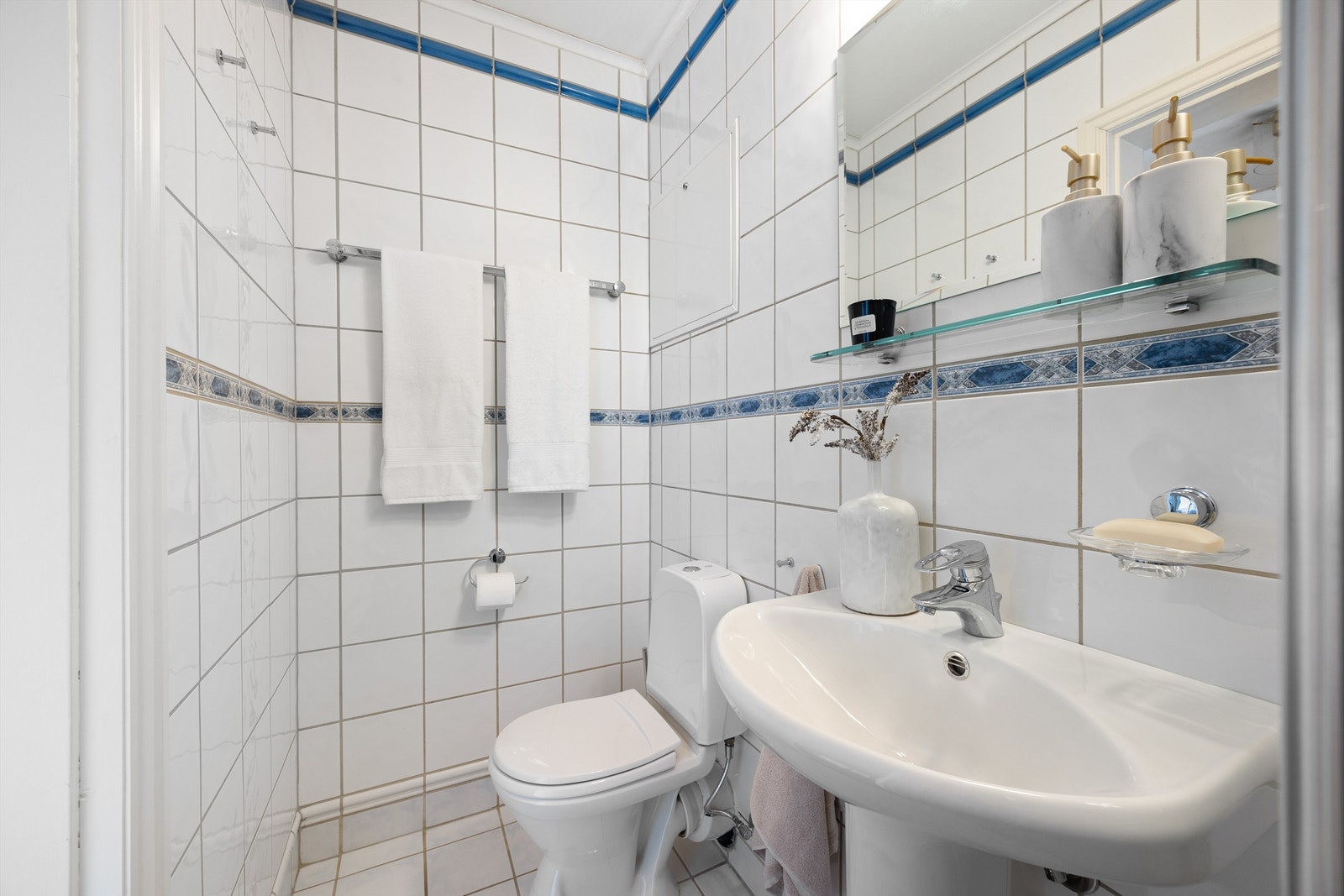 Flislagt bad med toalett, servant og dusj. Dette badet har inngang fra gangen. Galleribilde