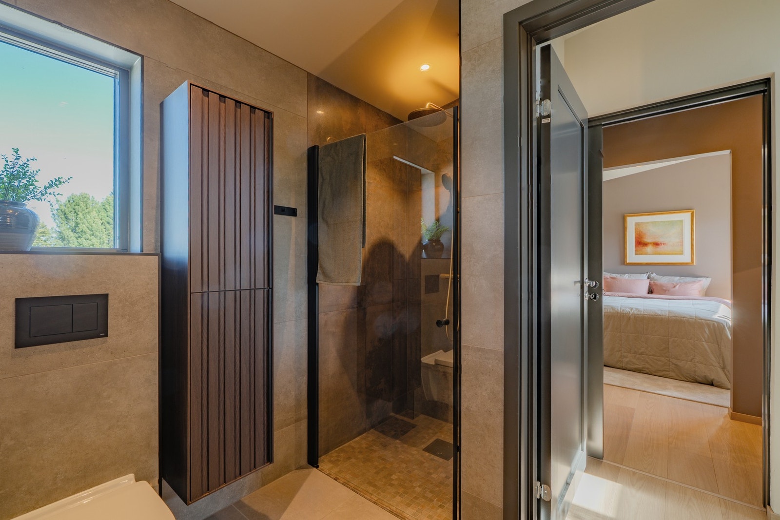 Romslig dusjnisje med moderne glassvegg og kvalitetsarmatur. Praktisk høyskap gir gode oppbevaringsmuligheter. Galleribilde