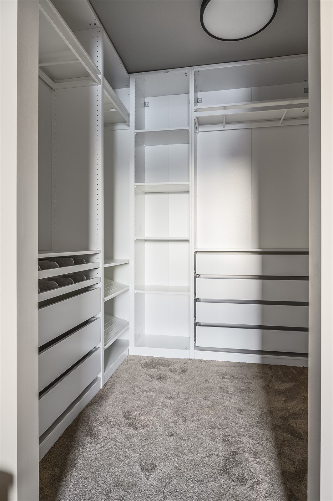 Walk-in closet med innredning fra 2024 og mykt, deilig teppe på gulvet. Galleribilde