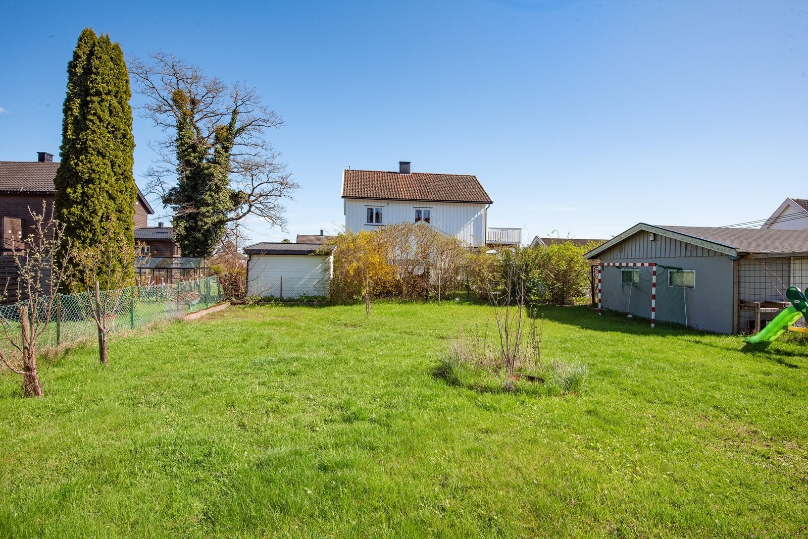 Den inngjerdede tomten har gode solforhold og er opparbeidet med plen, busker, bed, frukttrær og div. beplantning Galleribilde