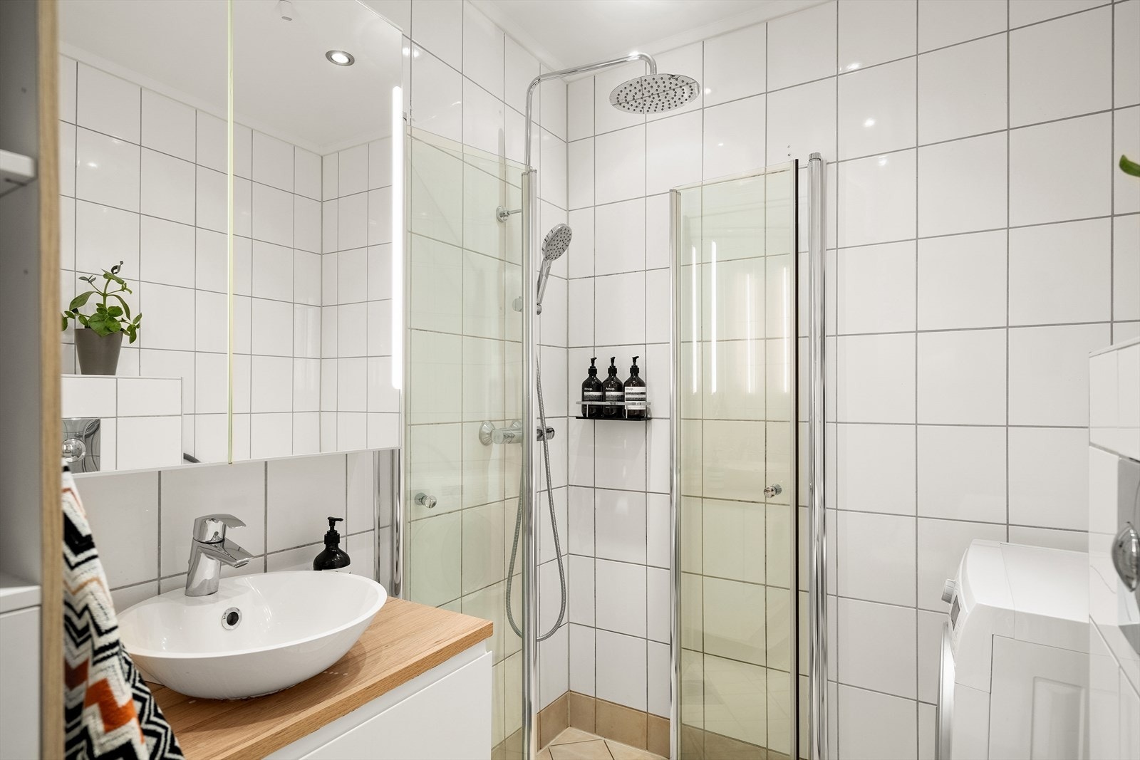 Baderommet er utstyrt med innfellbare dusjdører, mekanisk avtrekk, servantskap og veggmontert wc Galleribilde