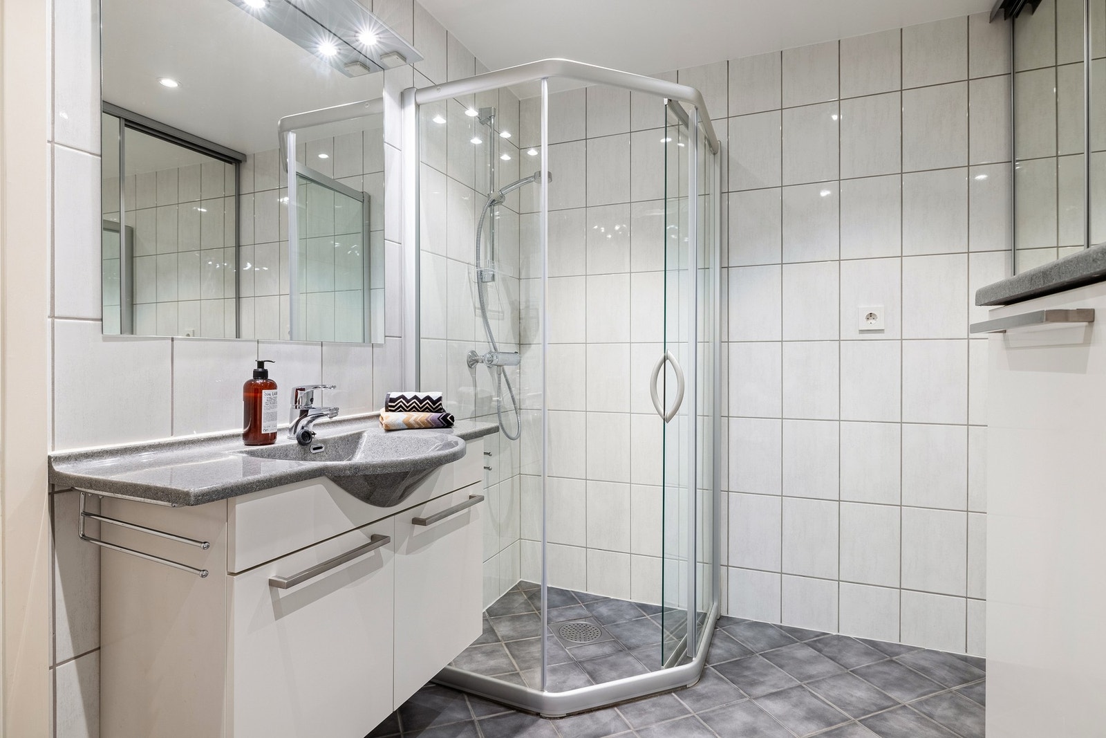 Leiligheten har to stilrene og helflisede bad. Hovedbadet inneholder dusjhjørne, vegghengt toalett, baderomsinnredning og opplegg for vaskemaskin. Galleribilde