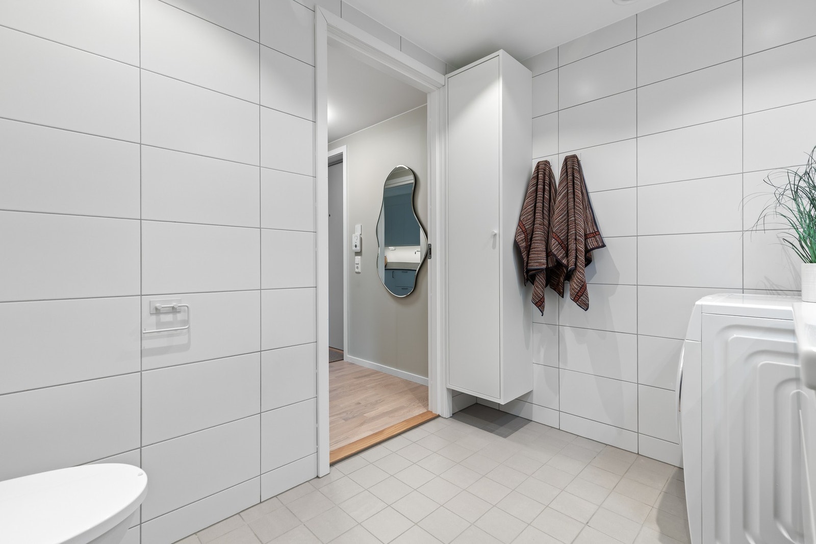 Badet er utstyrt med innfellbare dusjdører, servantskap, rørfordelingsskap, mekanisk avtrekk og veggmontert wc. Galleribilde