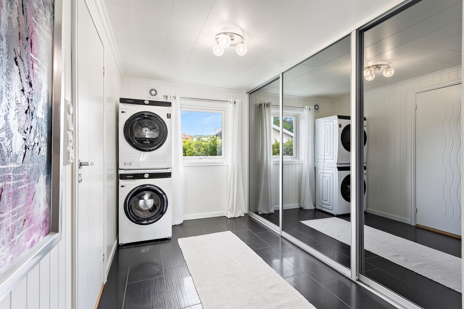 Mellom entré og bad er det et praktisk rom med fliser på gulv, oppbevaring i skyvedørsgarderobe og opplegg for vaskemaskin. Galleribilde