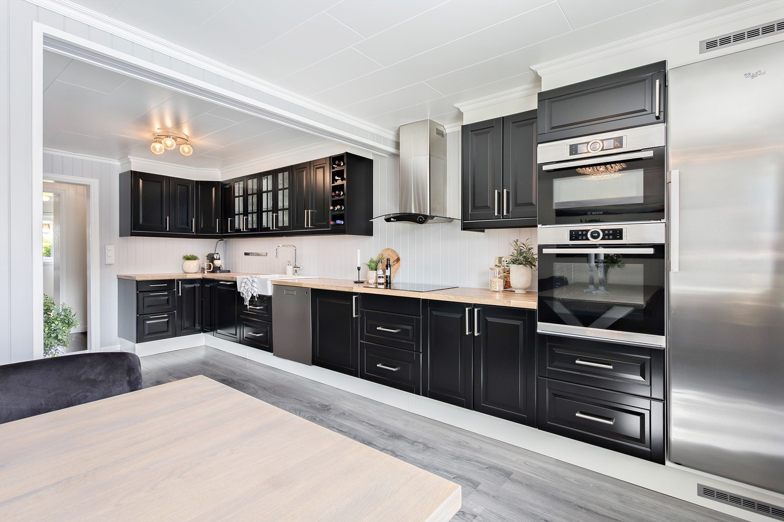 Stort kjøkken med profilerte fronter og benkeplate i laminat med nedfelt porselensvask. Galleribilde