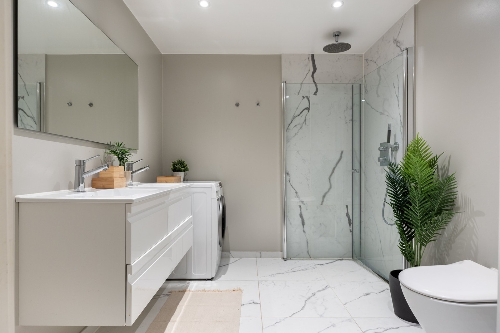 Stilrent baderom fra 2019 med flislagt gulv med gulvvarme og flislagte vegger i dusjsonen. Galleribilde