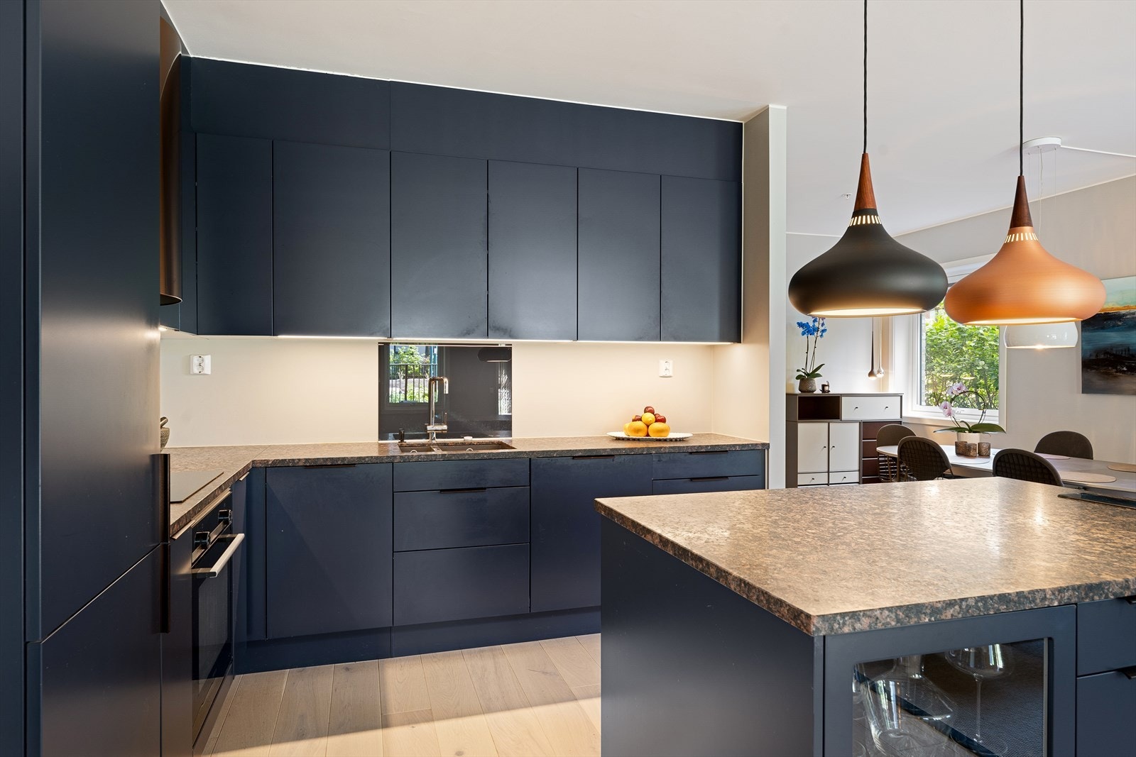 Tidsriktig innredning med mørkeblå, slette fronter, som i kombinasjon med benkeplaten i stein gir et tidløst og delikat uttrykk Galleribilde