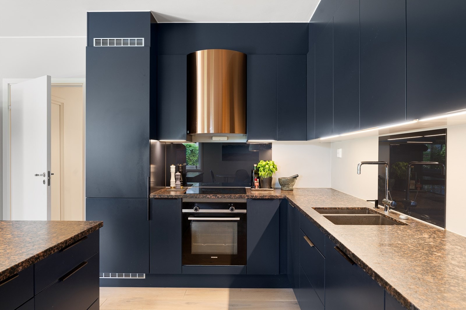 Kjøkkenet er utstyrt med integrerte hvitevarer som induksjonstopp, stekeovn, oppvaskmaskin og kombinert kjøle-/fryseskap Galleribilde