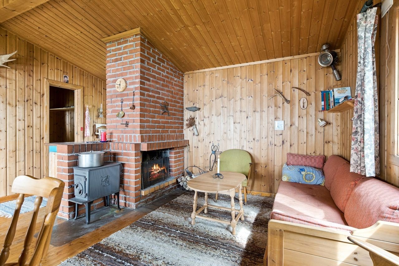 Det er både åpen peis og vedovn i hytta. Pipemuren danner et naturlig skille mellom stue- og kjøkkendel. Galleribilde