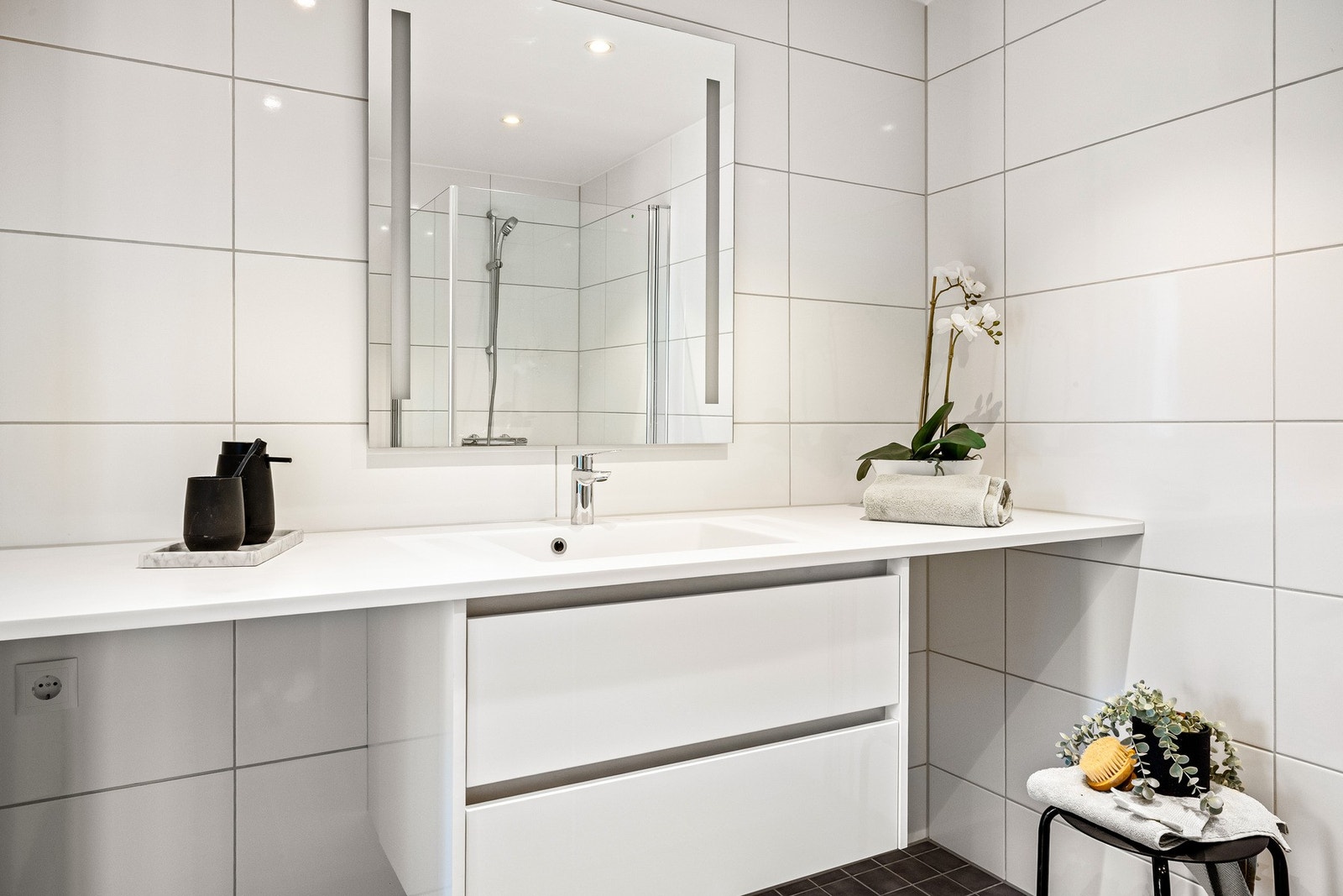 Badet er komplett med vegghengt toalett, dusj, servant med oppbevaring og opplegg til vaskemaskin og tørketrommel. Galleribilde