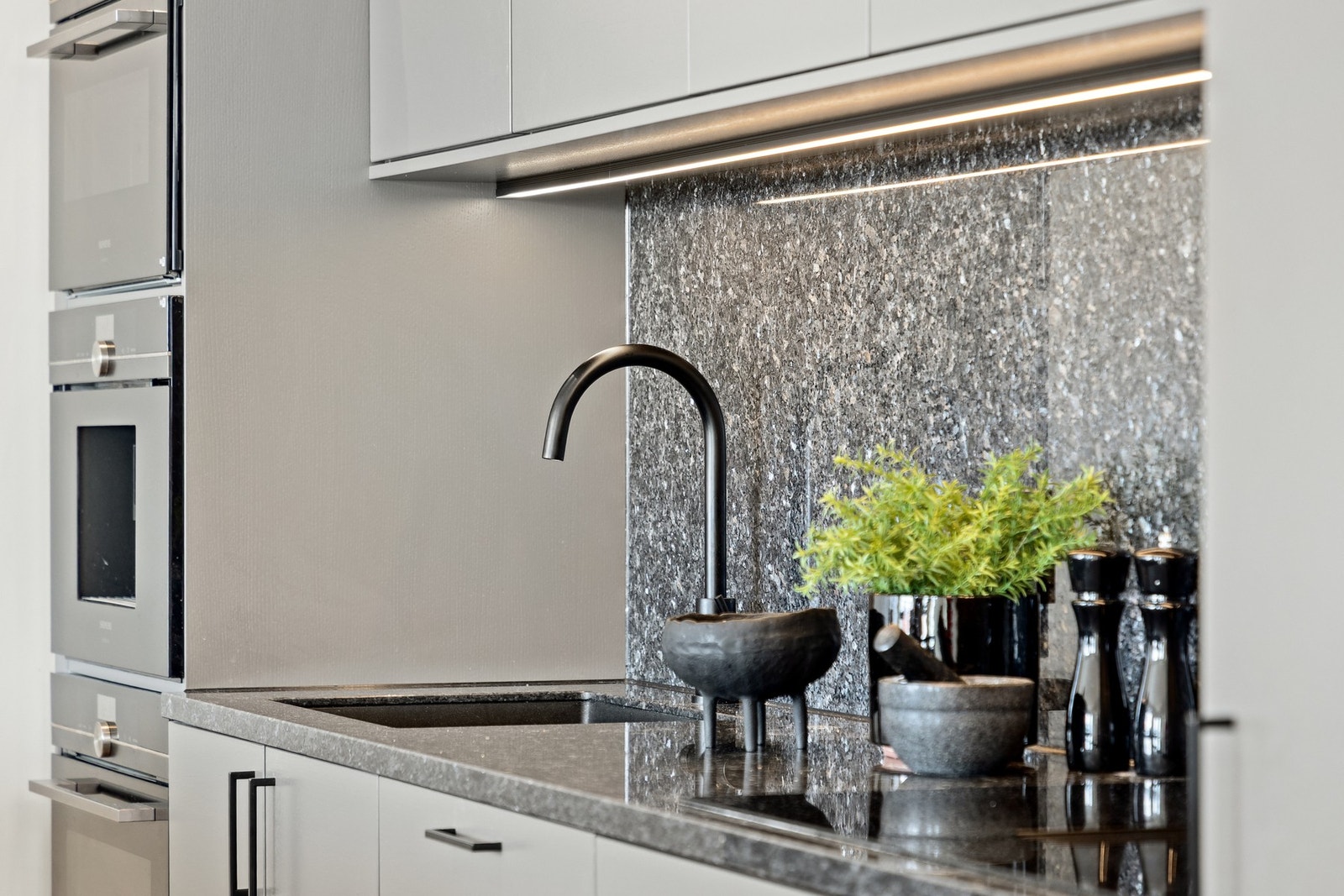 Kjøkkenet er utstyrt med integrert platetopp, stekeovner, kaffemaskin og kjøleskap, som gir et ryddig og helhetlig inntrykk. Galleribilde