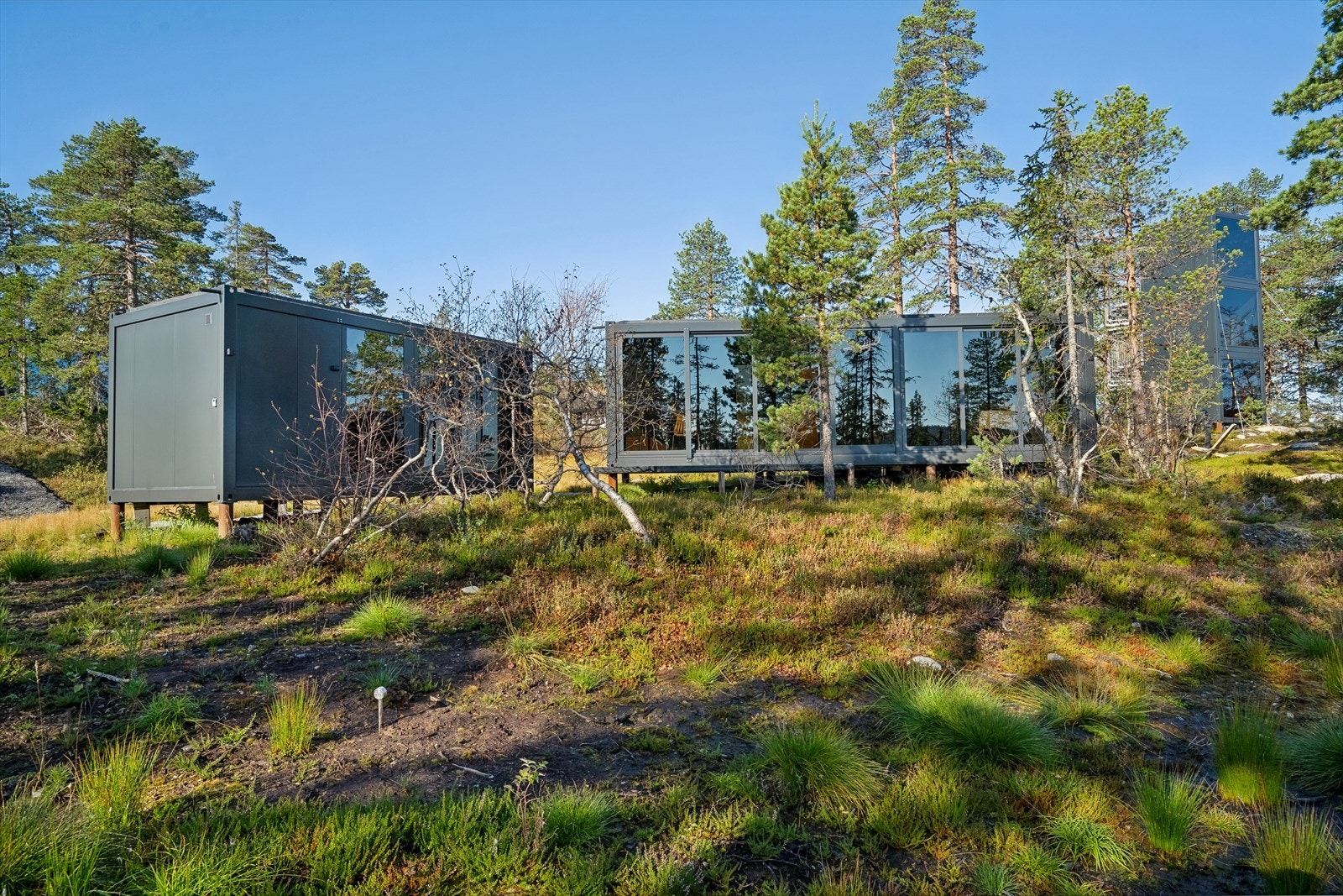 Designet for enkle, vakre og naturnære opphold. Hytte med panoramavinduer, solide materialvalg og gjennomtenkte løsninger. Annekset til venstre, hytten til høyre. Galleribilde