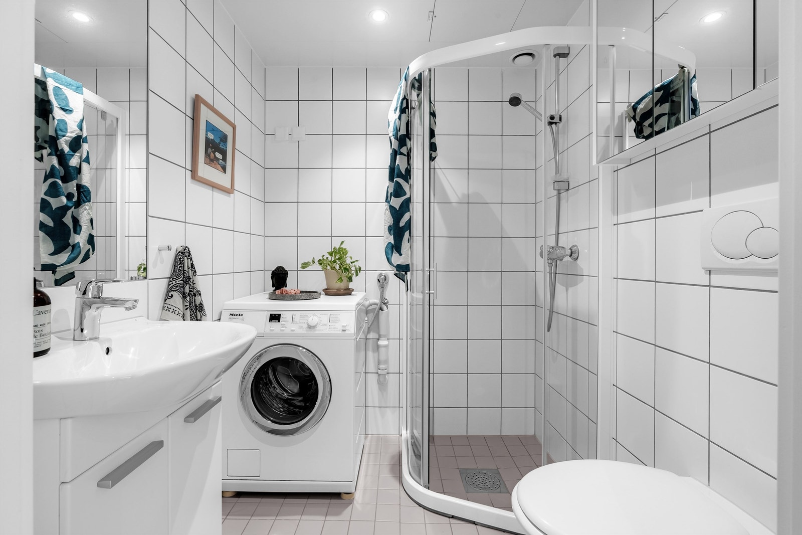 Pent, flislagt baderom med gulvvarme og downlights. Det er veggmontert toalett samt dusjhjørne, og opplegg for vaskemaskin. Galleribilde