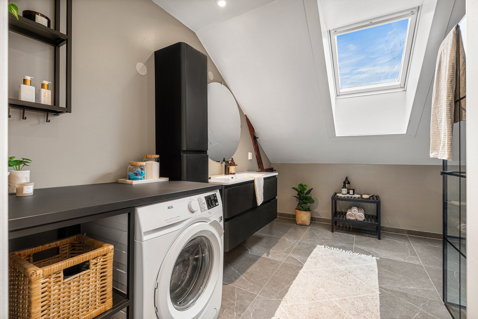 Lyst og stilrent bad med moderne innredning, takvindu, kran og avløp for vaskemaskin. Galleribilde