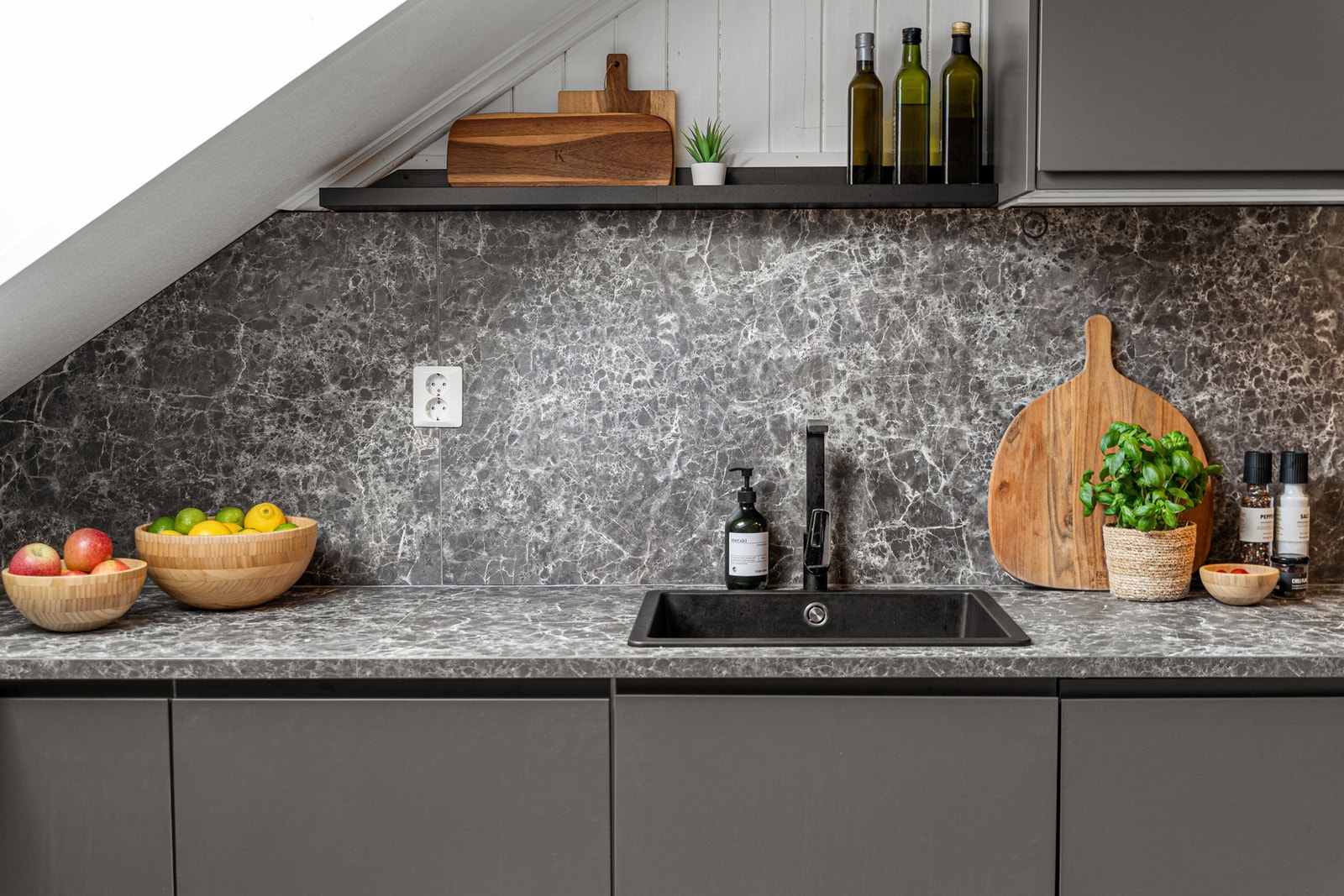 Moderne kjøkkenbenk med rene linjer, funksjonell innredning og elegant kontrast mellom mørke flater og naturlige innslag. Galleribilde