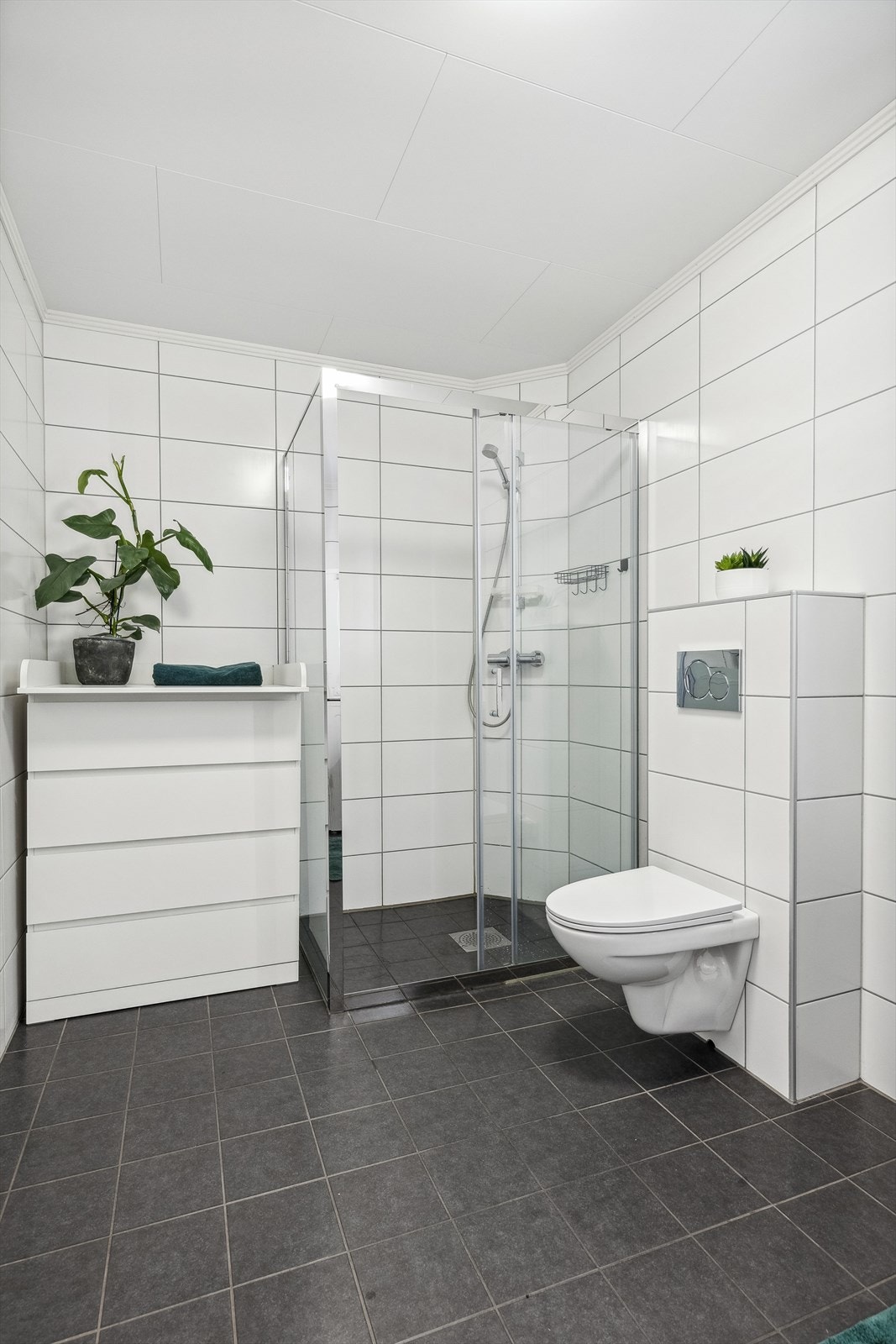 Et romslig og funksjonelt bad med god standard som er utstyrt med dusj, vegghengt toalett og opplegg for vaskemaskin. Galleribilde