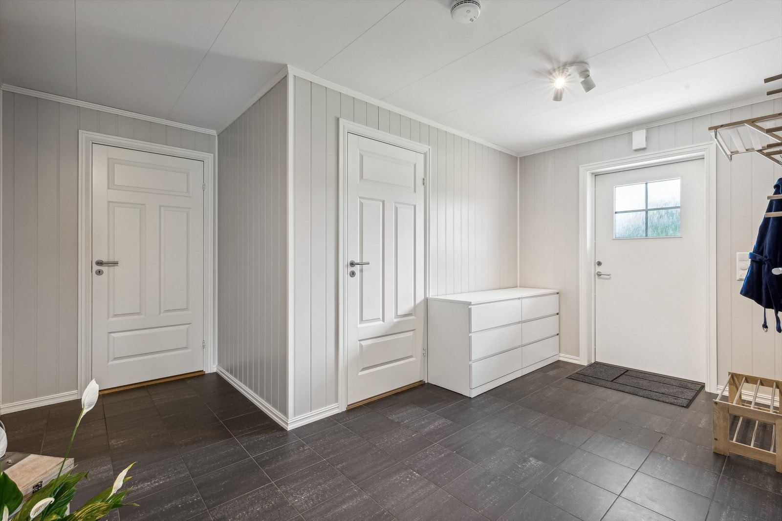 Vel innenfor døren blir du møtt av en romslig og stilfull entré. Her har du rikelig med plass til oppbevaring av sko og yttertøy. Boligen har også en praktisk innvendig bod, som er lett tilgjengelig fra entréen og tilbyr enda flere oppbevaringsmuligheter. Galleribilde