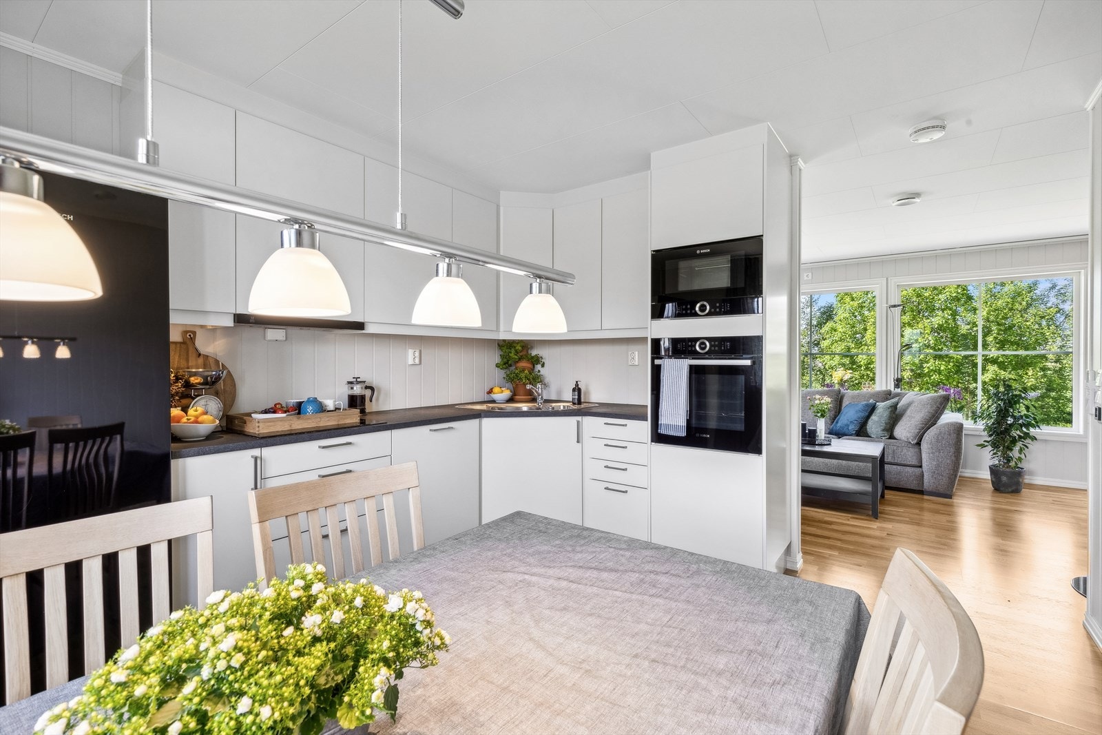 Kjøkken ligger delvis adskilt fra stuen, og har en pen kjøkkeninnredning med hvite, glatte fronter og en mørk laminert benkeplate. Her har du rikelig med både skap- og benkeplass, noe som gjør matlagingen til en glede. Galleribilde