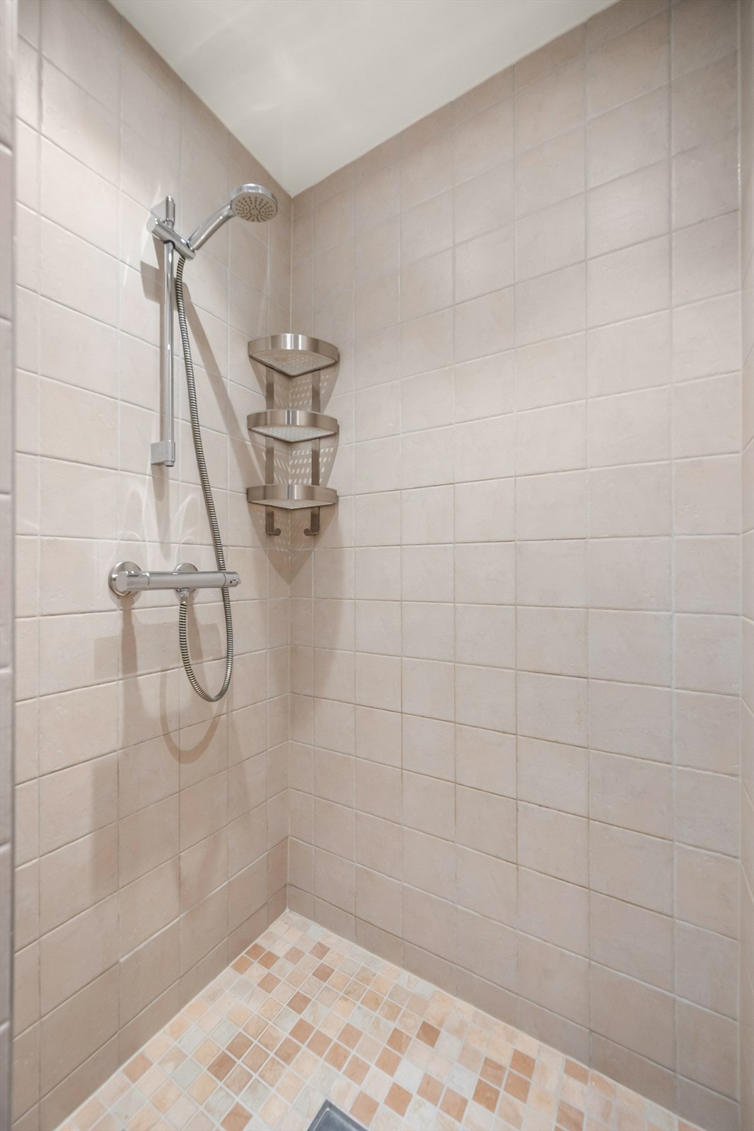 Badet er utstyrt med dusjhjørne med blandebatteri fra Damixa, veggmontert toalett og servantskap med hvit servant og blandebatteri. Galleribilde