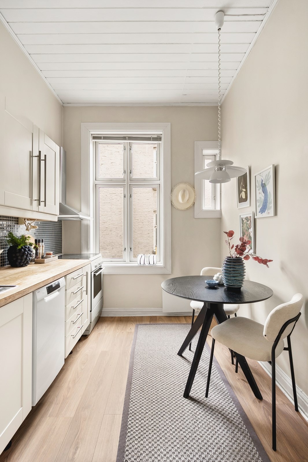 Klassisk innredning med lyse, laminerte profilerte fronter, fliser på vegg over kjøkkenbenk og heltre benkeplate. Galleribilde