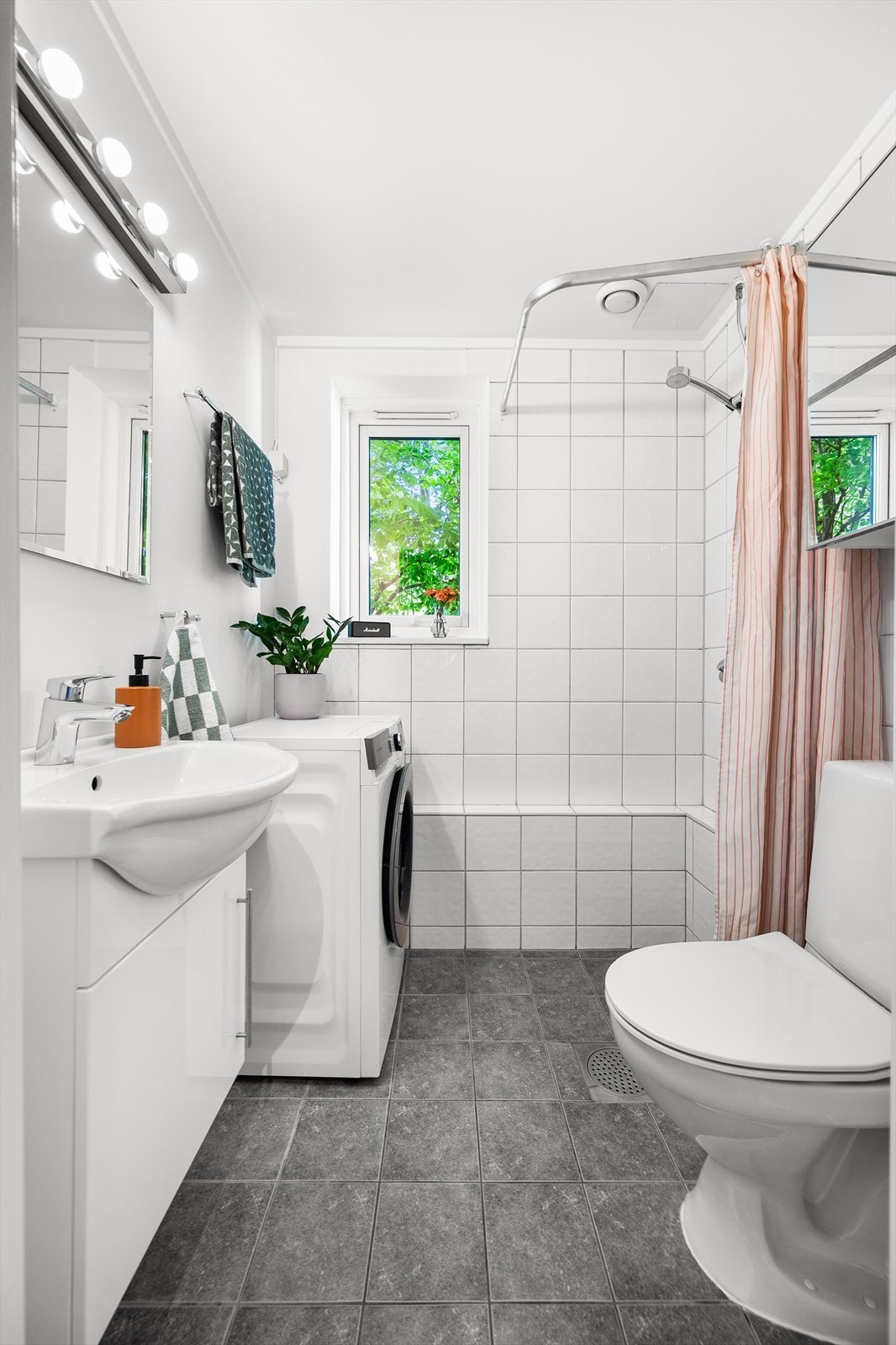 Pent og tidløst bad med flislagte overflater, elektrisk gulvvarme og opplegg for vaskemaskin. Galleribilde