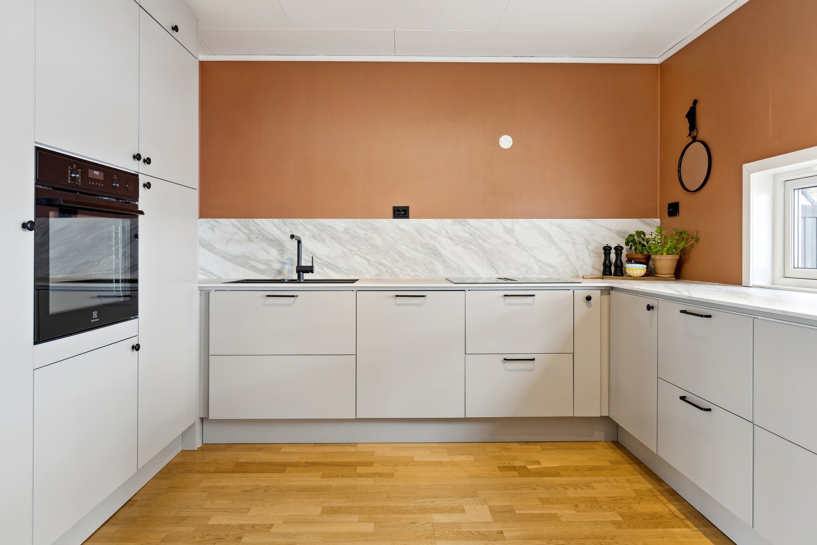 Integrerte hvitevarer, sort blandebatteri, sorte støpsel og åpent over kjøkkenbenken gir et helhetlig inntrykk. Galleribilde