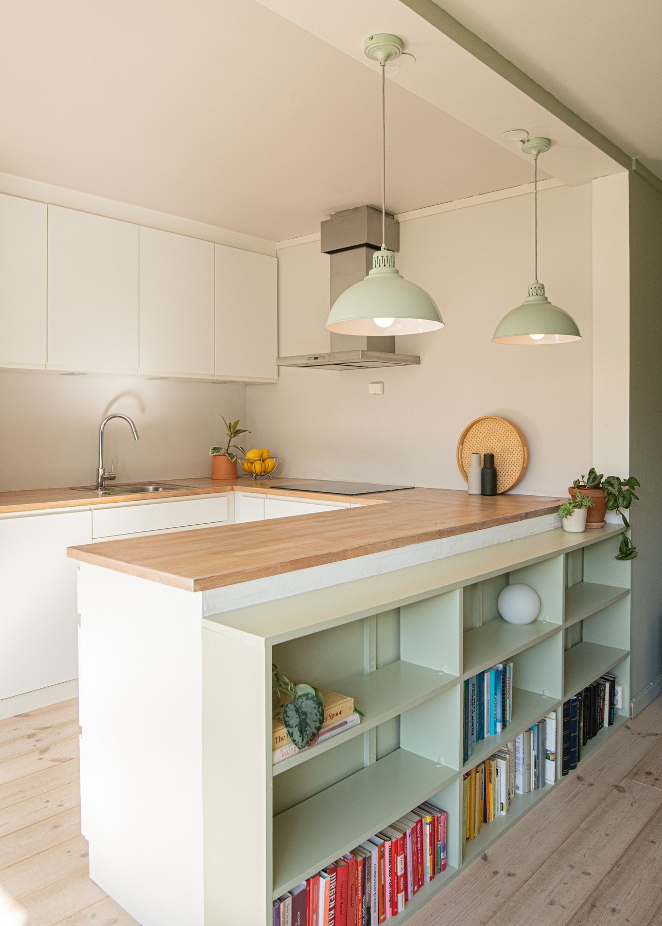 I forkant av kjøkkenøyen er det en plassbygd bokhylle som gir praktisk og dekorativ oppbevaringsplass. Galleribilde