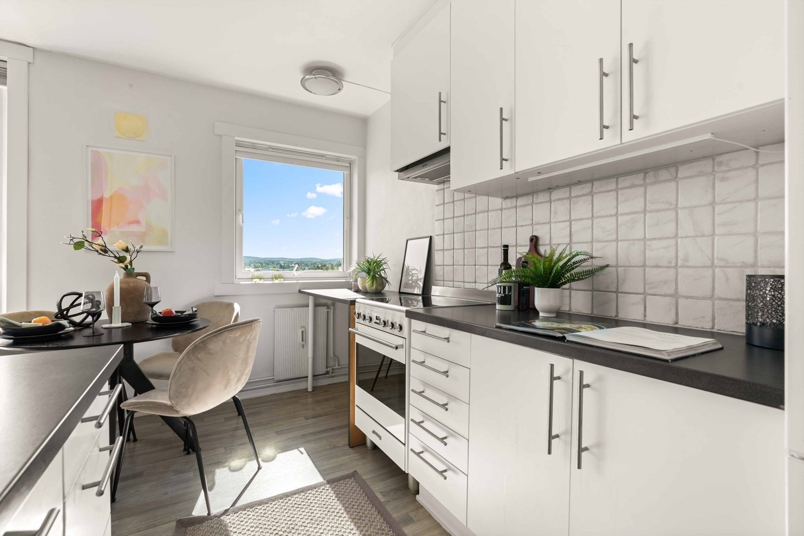 Her er det en stilfull kjøkkeninnredning med hvite, glatte fronter og hvit laminat benkeplate med nedfelt kum i rustfritt stål. Galleribilde