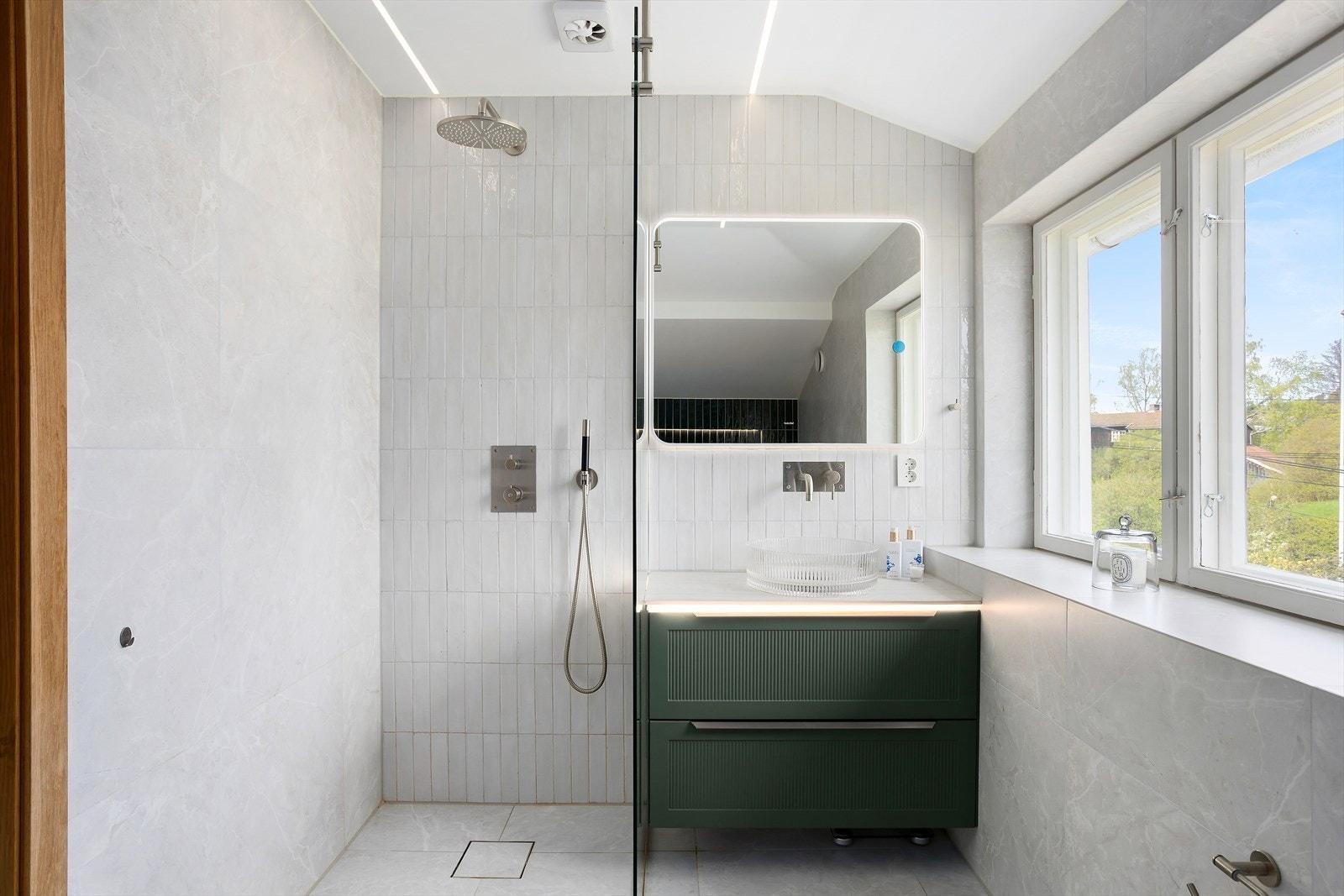 Badet har lyse 60x60 cm fliser på gulv med behagelig gulvvarme, samt en kombinasjon av grønne og lyse veggfliser. Galleribilde