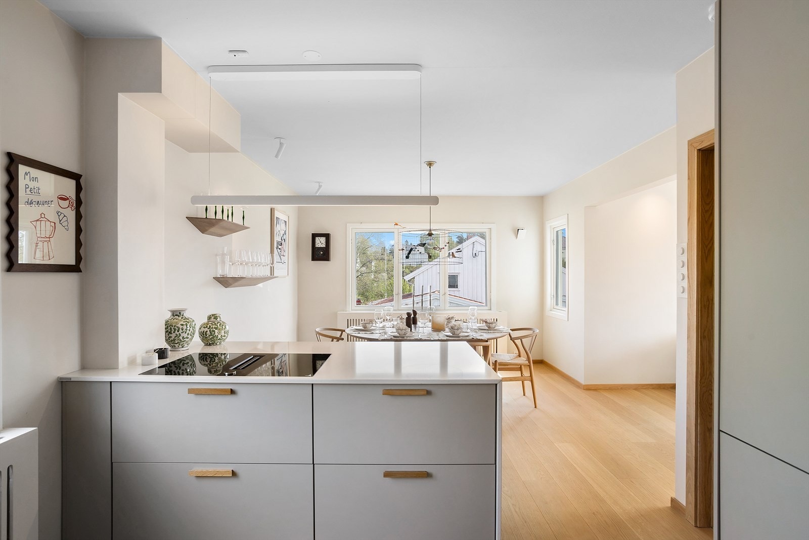 En stilren kjøkkenøy markerer overgangen til spiseområdet og gir både ekstra benke- og oppbevaringsplass. Galleribilde