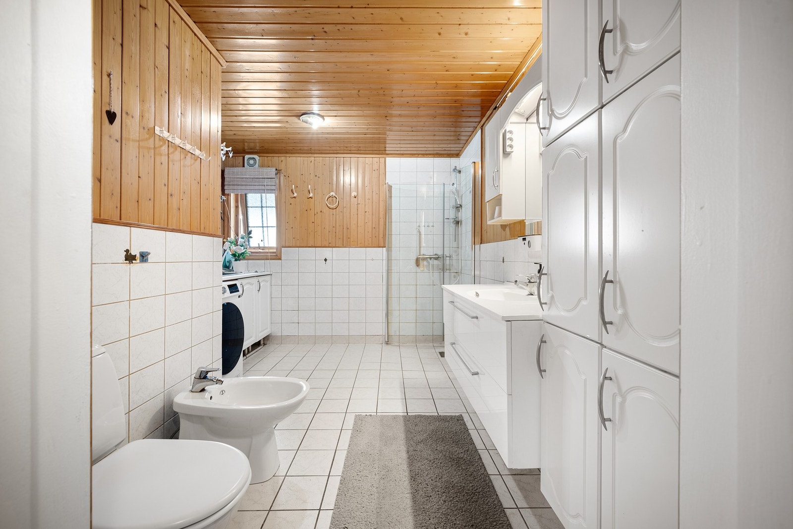 Stort og godt bad med delvis flislagte vegger og flislagt gulv Galleribilde