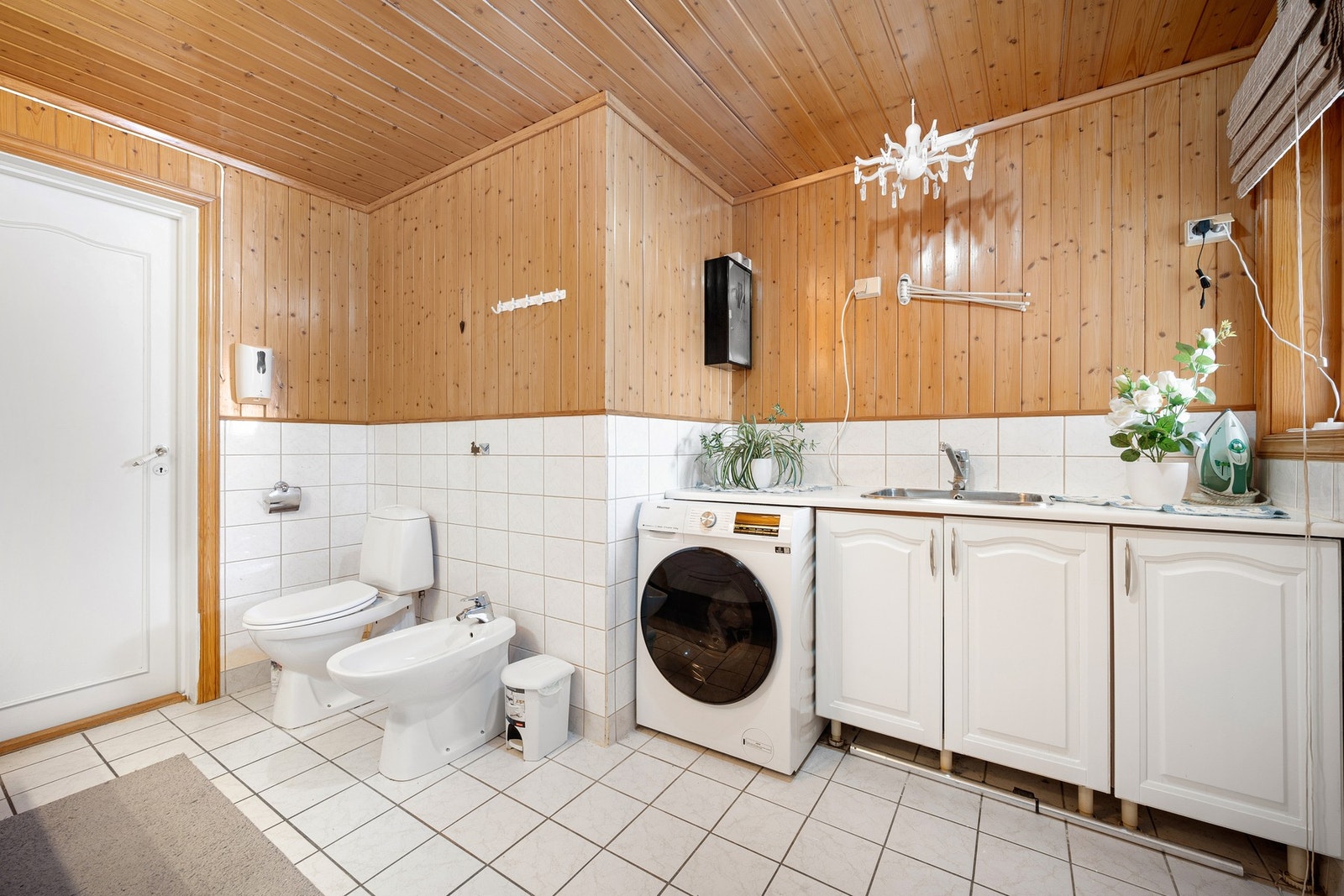 Kombinert bad og vaskerom med røropplegg for vaskemaskin og egen innredning med utslagsvask Galleribilde