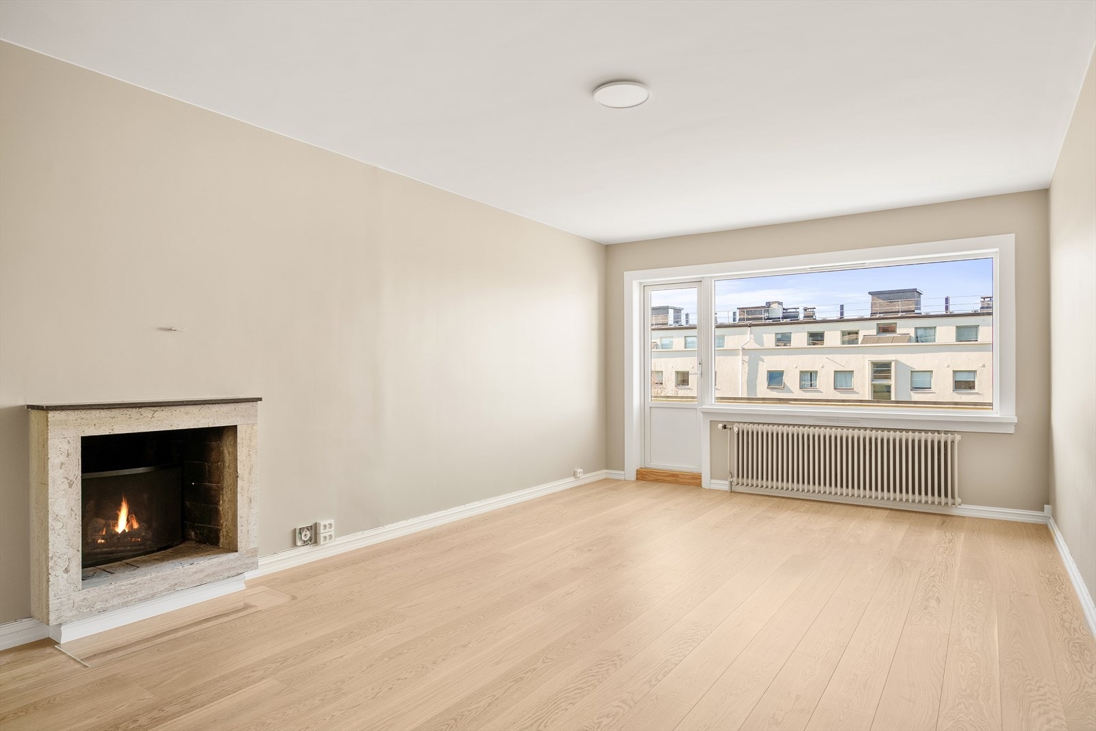 Romslig og lys stue med peis og utgang til balkong Galleribilde