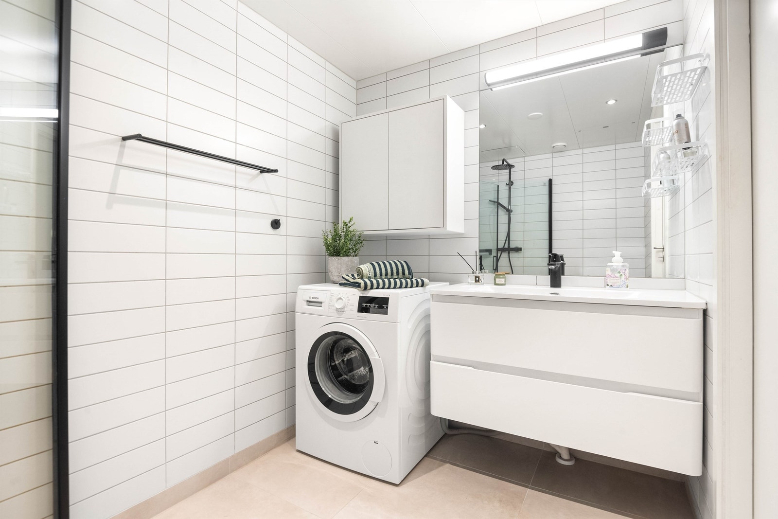 Flislagt gulv med varme og flislagte vegger, malte metallplater i himling med downlights og vegghengt servantinnredning. Galleribilde