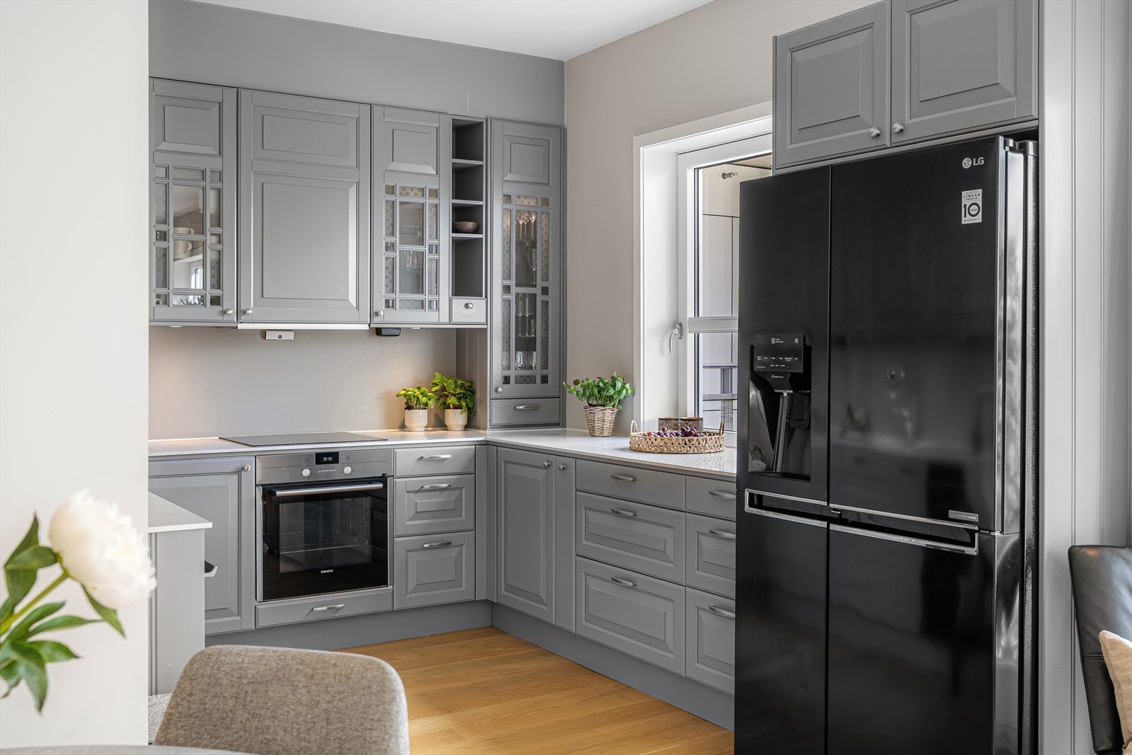 Den elegante innredningen fra Drømmekjøkkenet imponerer med profilerte fronter i en tidløs gråfarge, glassdører med sprosser og solide detaljer. Galleribilde