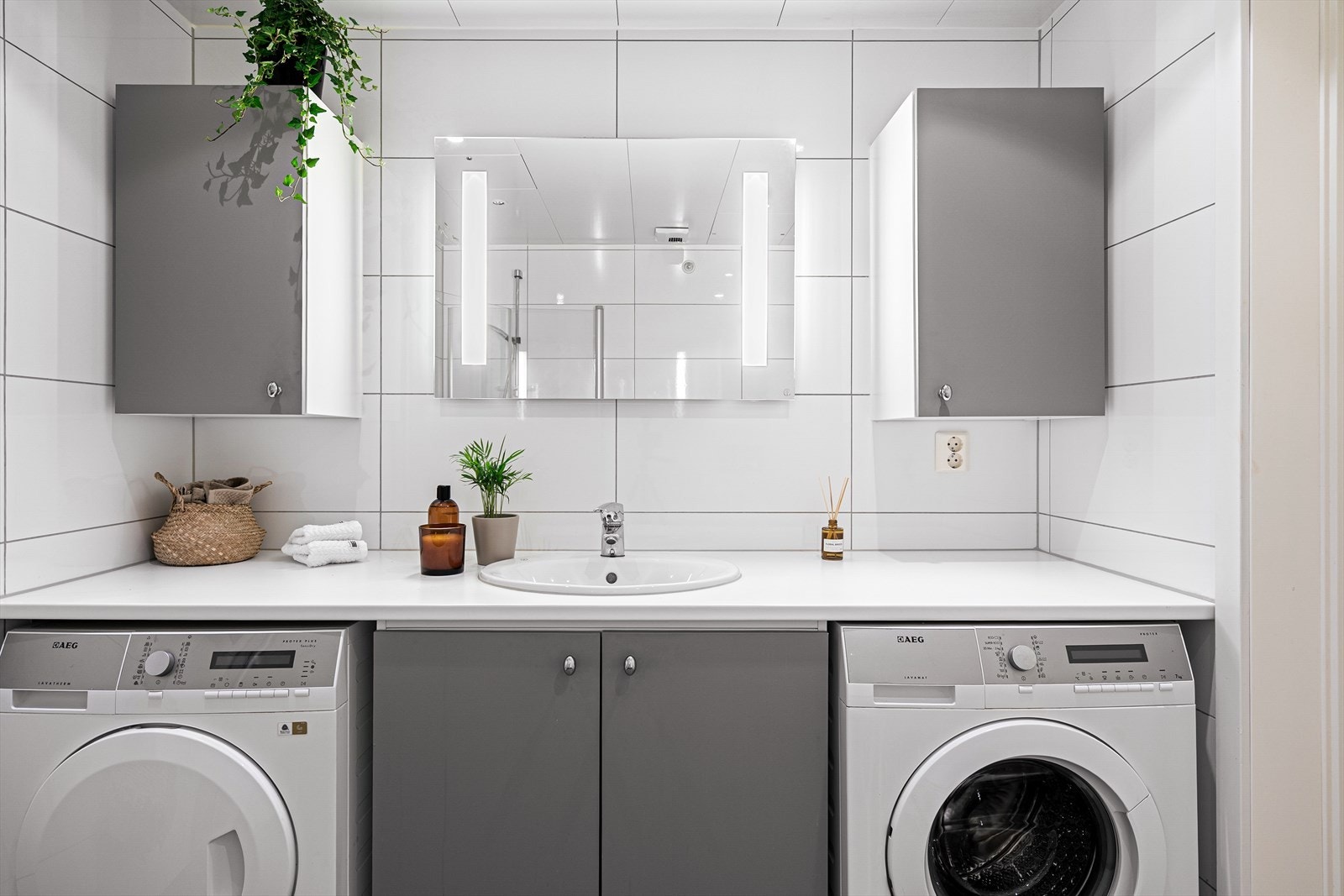 Under den romslige benkeplaten er det integrert både vaskemaskin og tørketrommel fra AEG, praktisk plassert for effektiv hverdag og skjermet for rolig uttrykk. Galleribilde