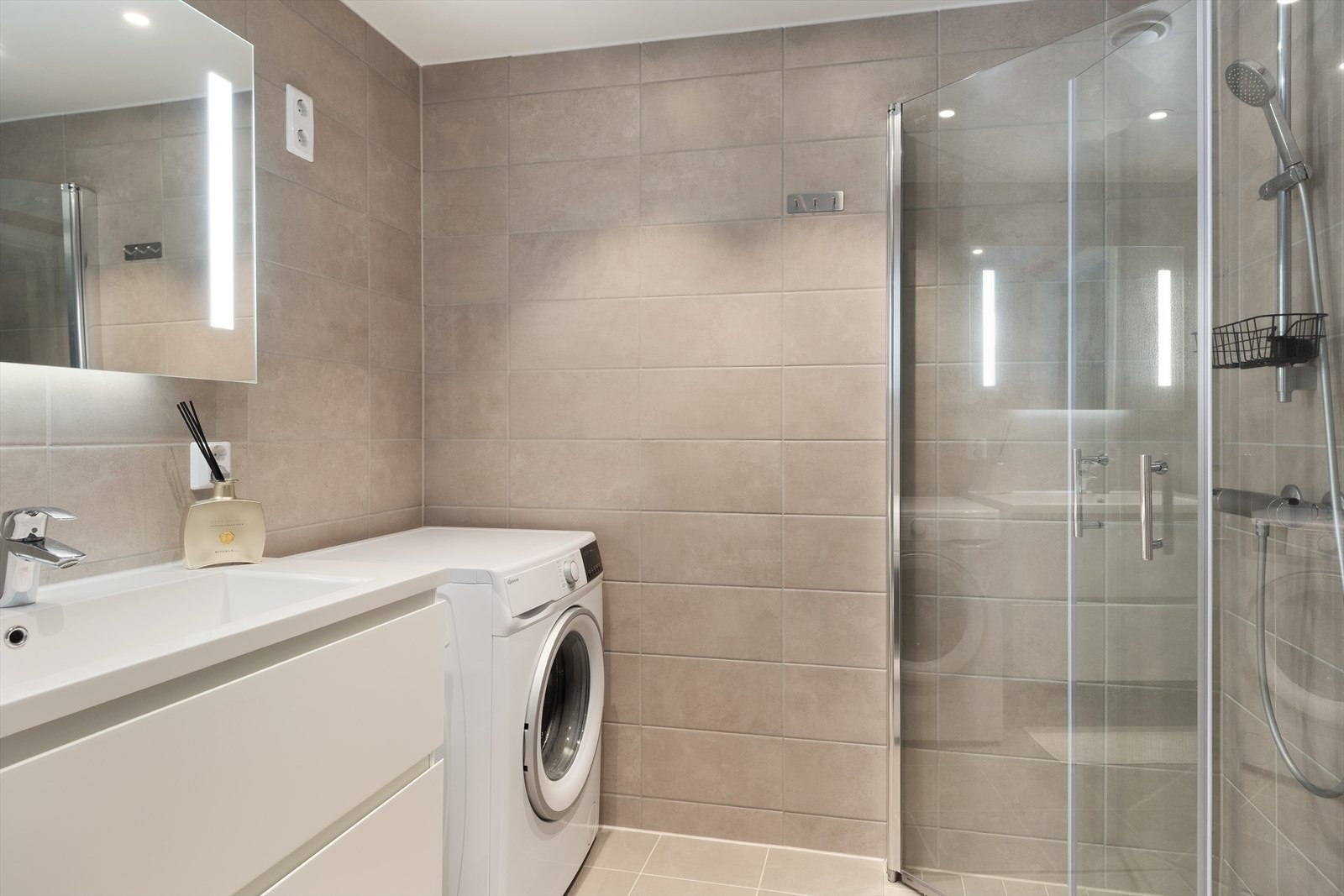 Badet som er utstyrt med vegghengt toalett, dusjhjørne med innfellbare glasveggar, nedfelt servant med underskuffer, spegel med lyslist og opplegg for vaskemaskin. Galleribilde