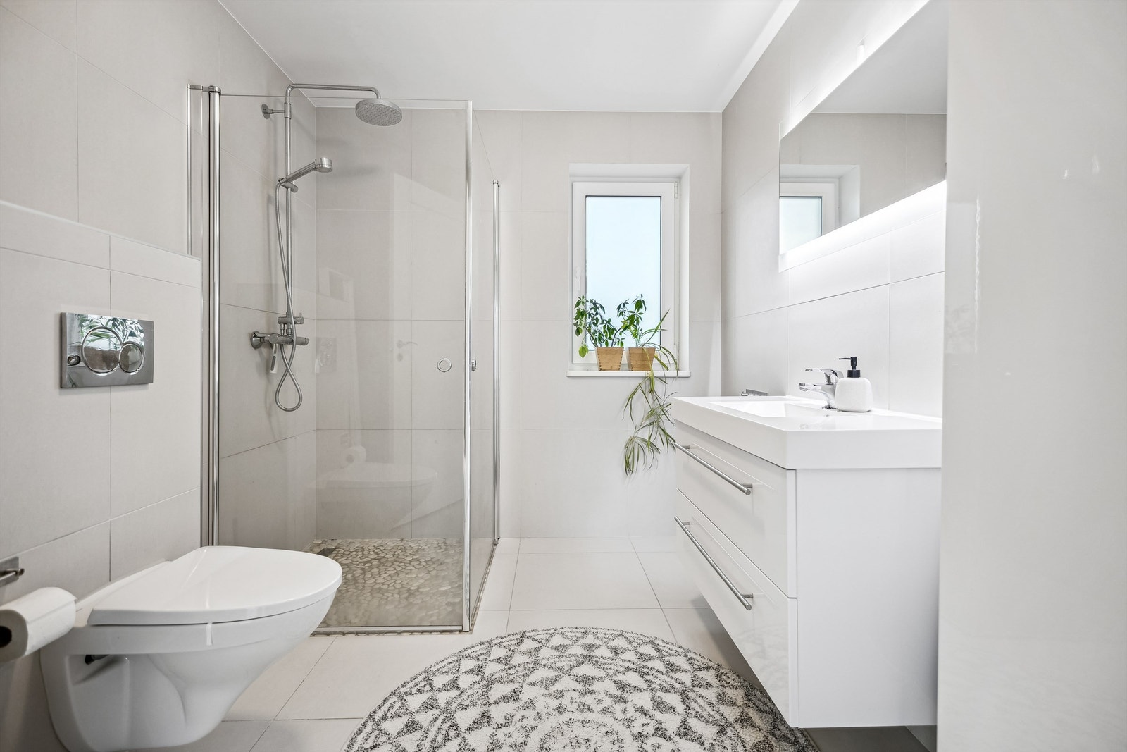 Lekkert, flislagt bad med gulvvarme, lys og moderne baderomsinnredning, dusjhjørne med regndusj og vegghengt toalett. Galleribilde