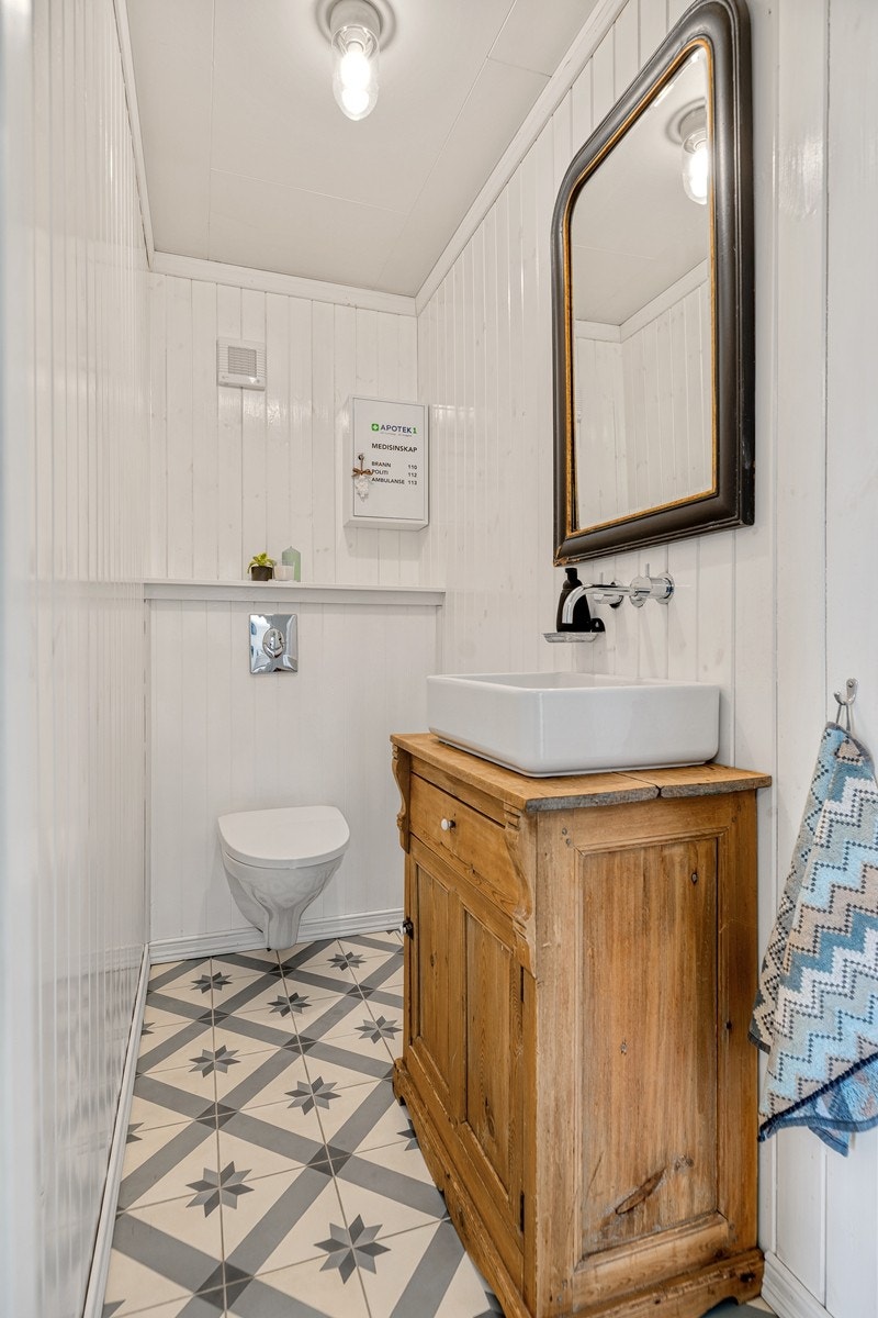 Gjestetoalett med vegghengt wc, servant med skap og skuff under. Galleribilde