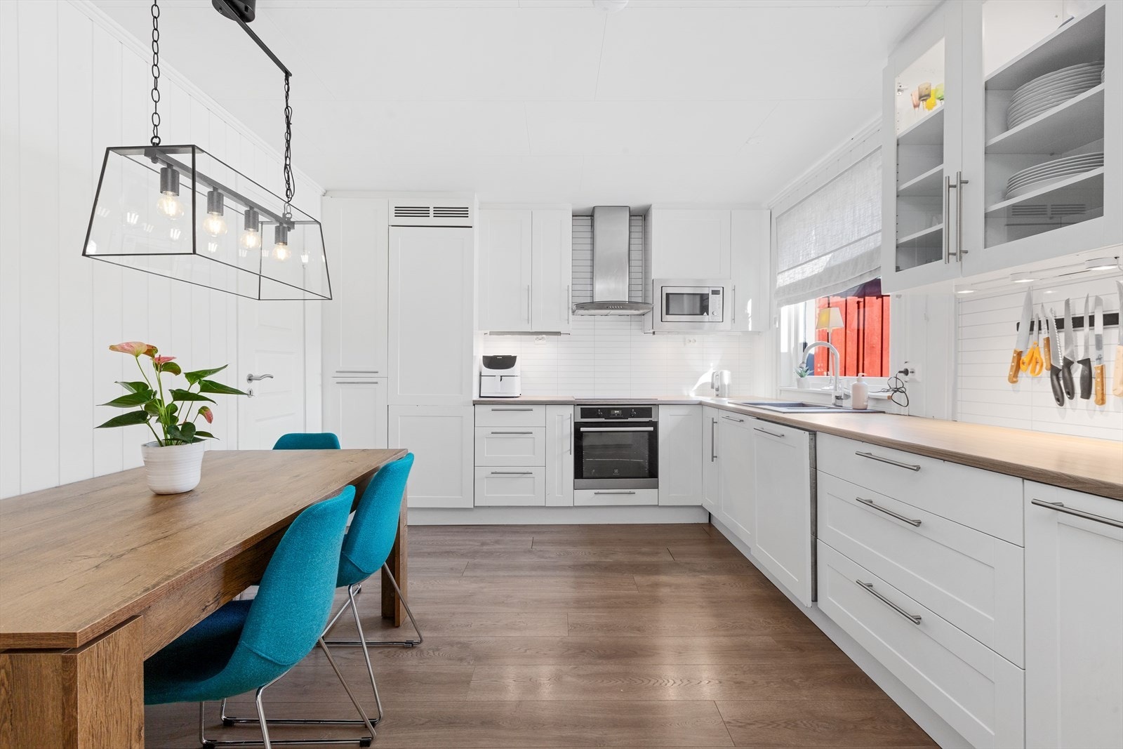 Kjøkken med laminatgulv og Mdf plater på vegger. Hvit kjøkkeninnredning med medfølgende hvitevarer (komfyr, platetopp, kjøle/fryseskap og oppvaskmaskin) Galleribilde