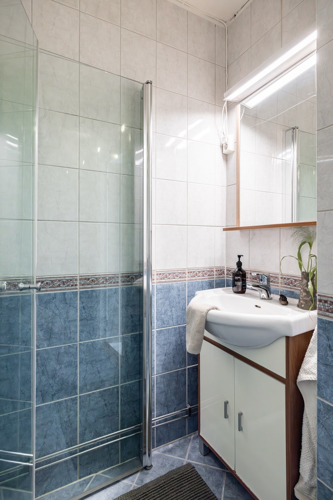 Badet er innredet med servant i skapseksjon og gulvmontert toalett. Videre er det dusjhjørne med innfellbare glassdører. Galleribilde