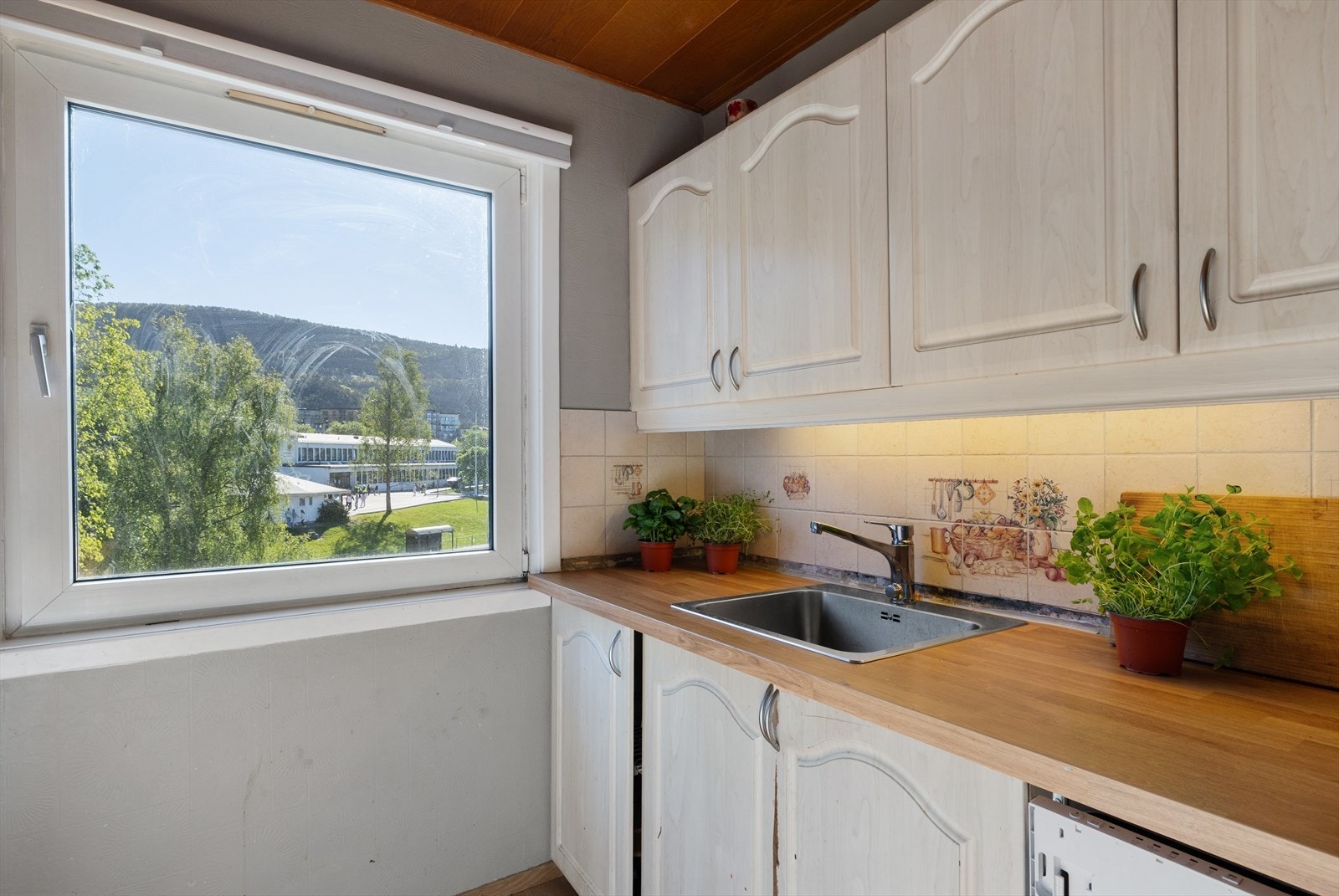 Kjøkkenet er i dag innredet med profilerte fronter, laminat benkeplate, stålvask og ventilator - samt tilrettelagt for oppvaskmaskin. Galleribilde